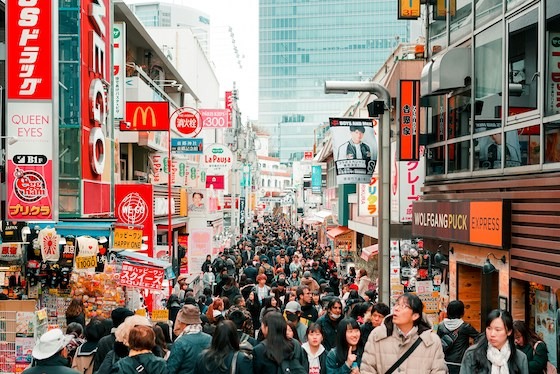 A bustling crowd moves through the vibrant shopping street of Takeshita Street in Harajuku, Tokyo.