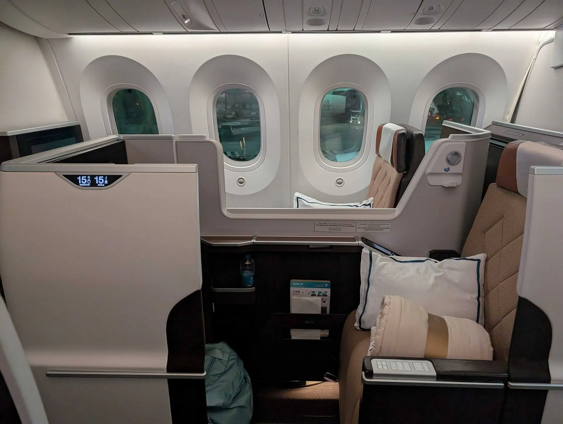 A luxurious business class seat aboard an aircraft, likely a Boeing 787 Dreamliner, features plush bedding and a sleek design for an enhanced travel experience.