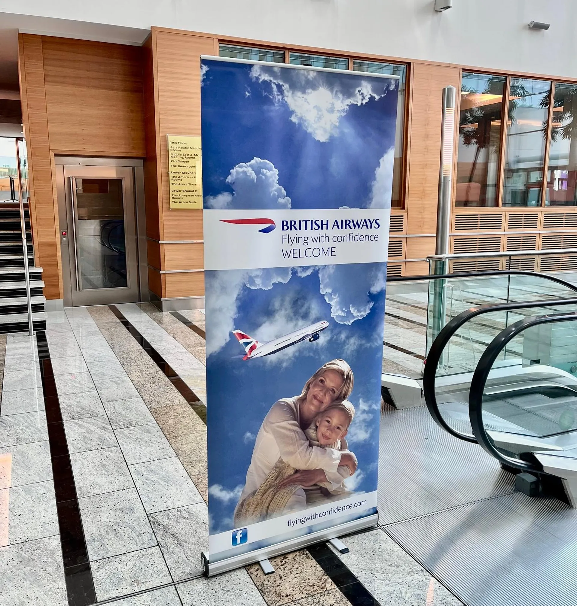 A British Airways advertisement stands next to an escalator.