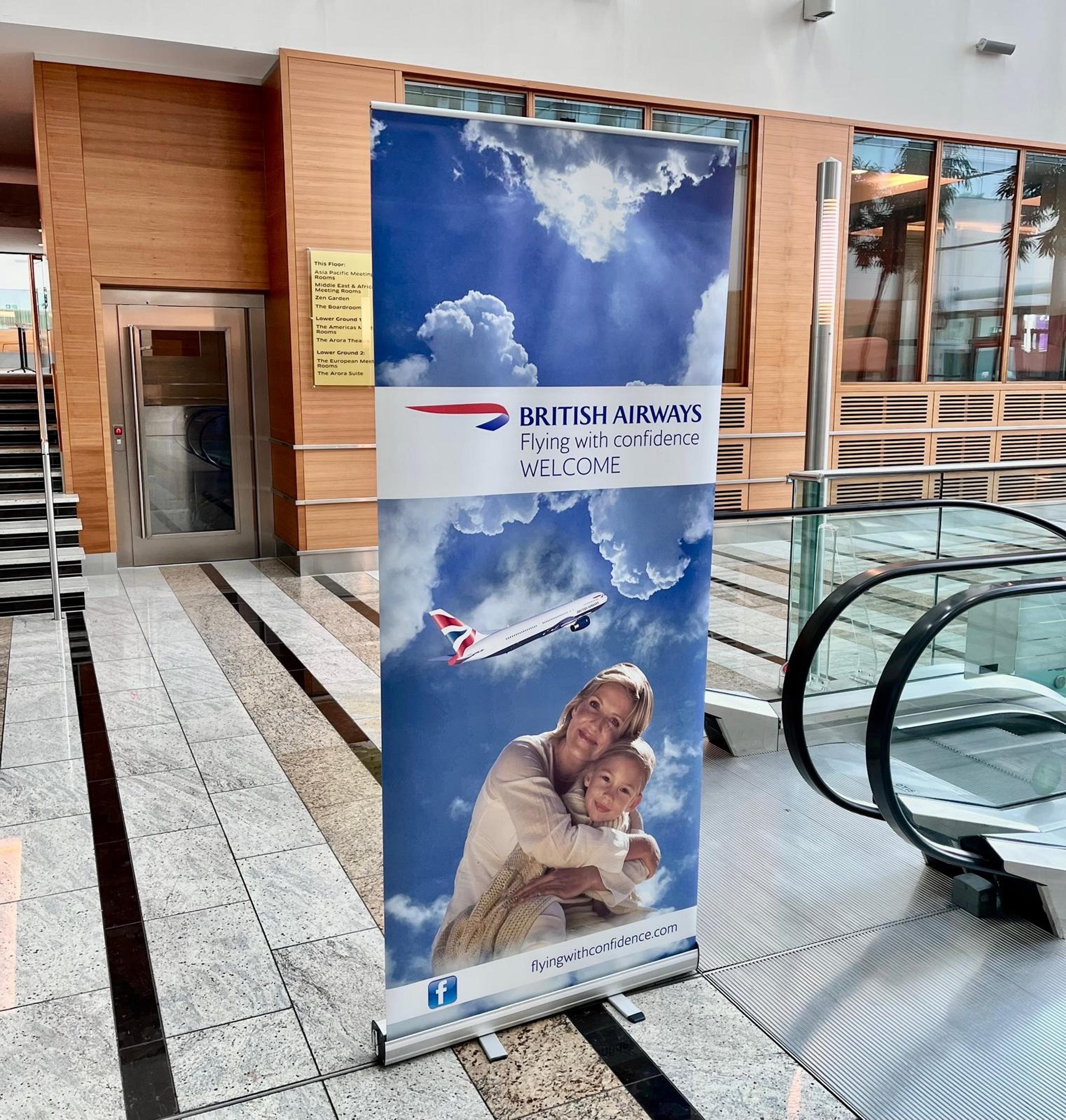 A British Airways advertisement stands next to an escalator.