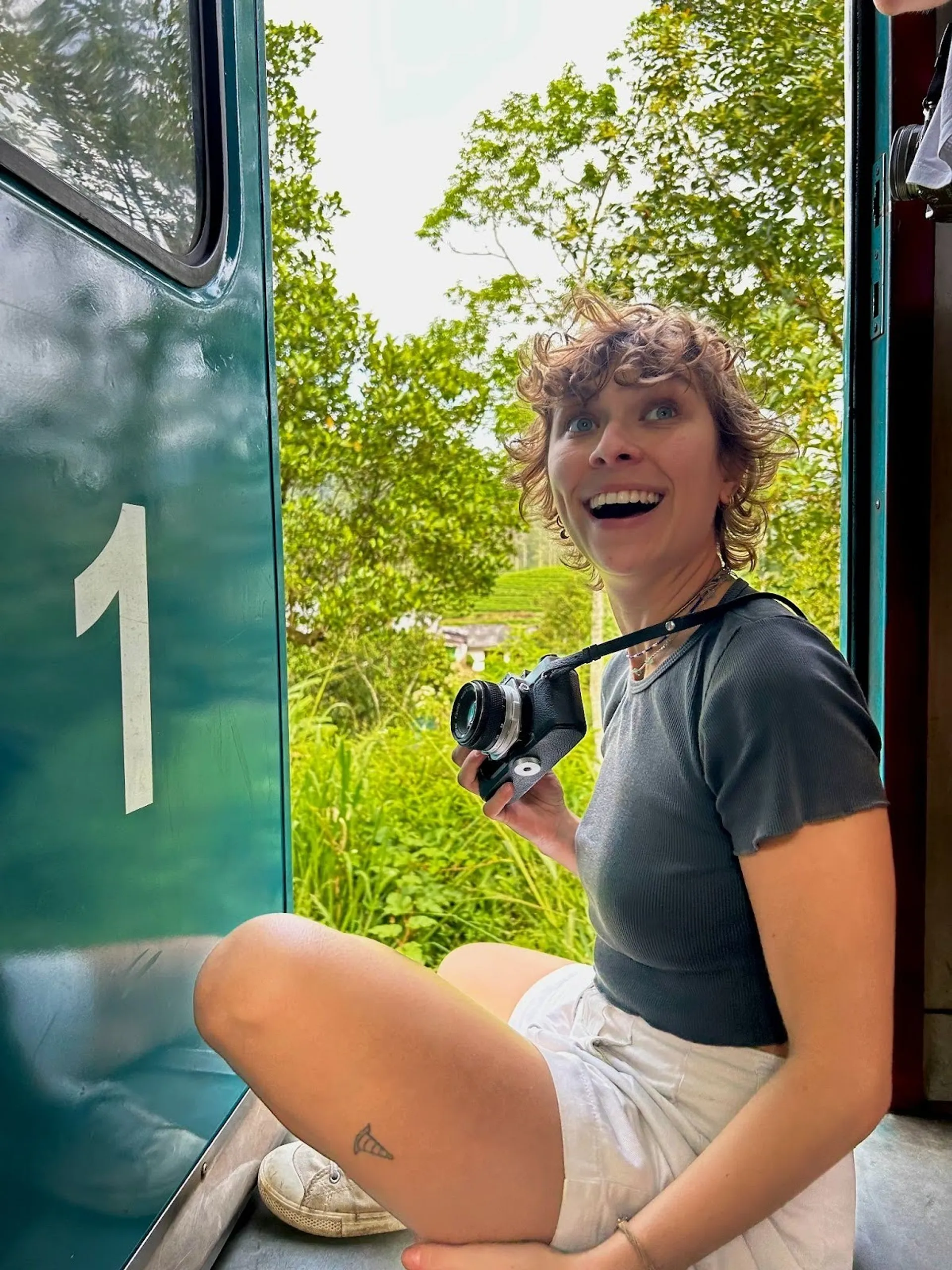 A person with a camera enjoys a train ride through the lush landscapes of Sri Lanka.