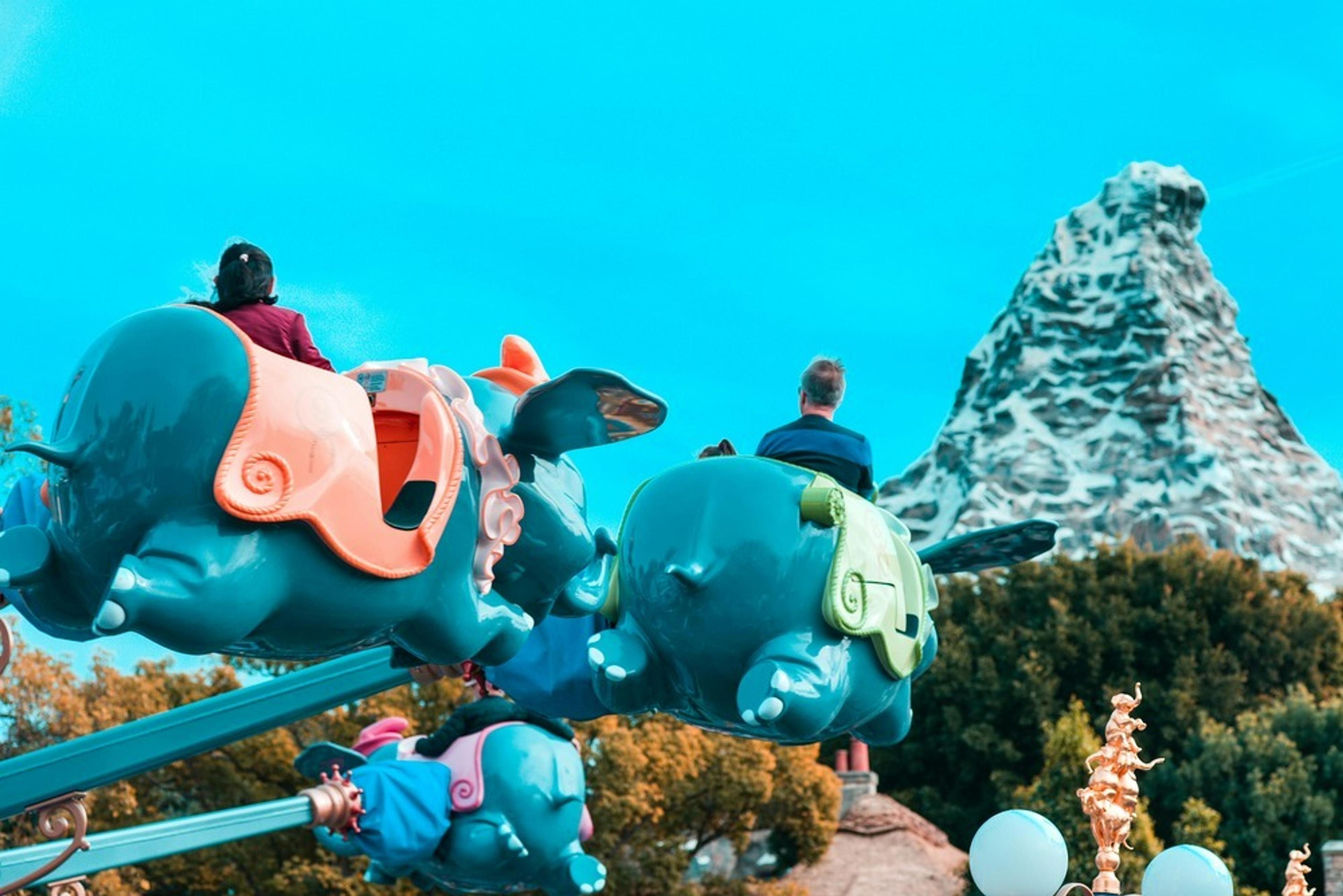 Children ride flying elephant-themed cars near the Matterhorn Bobsleds at Disneyland.