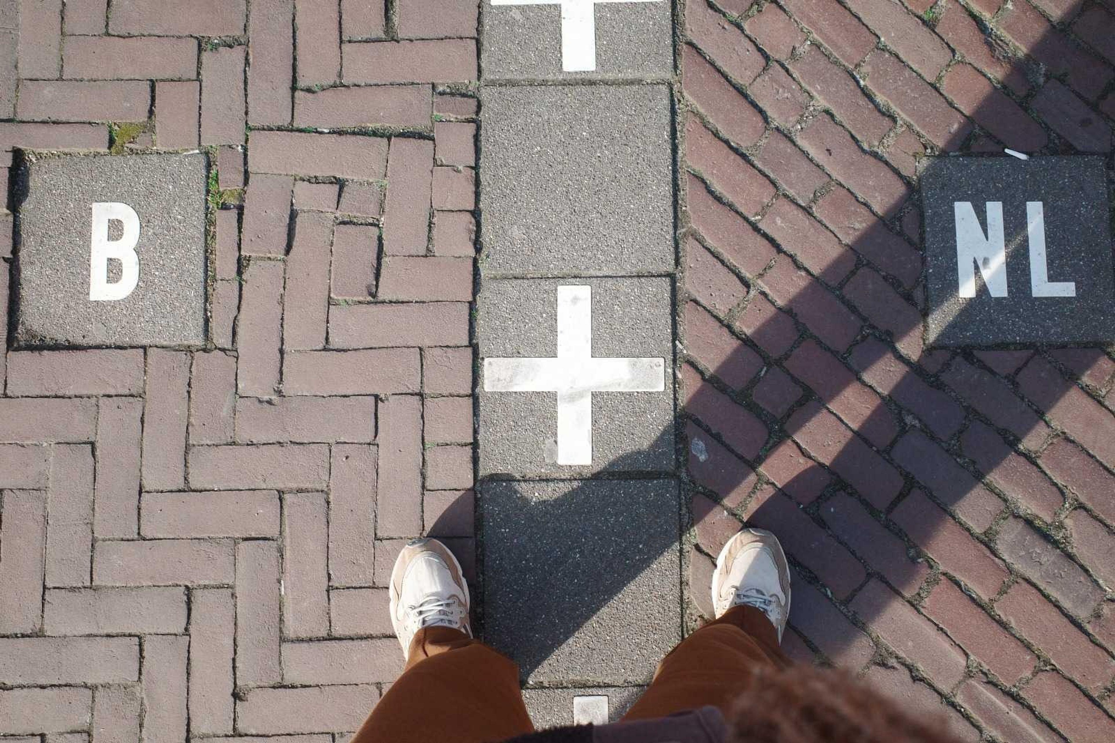 Feet standing on the international border between Belgium and the Netherlands in Baarle.