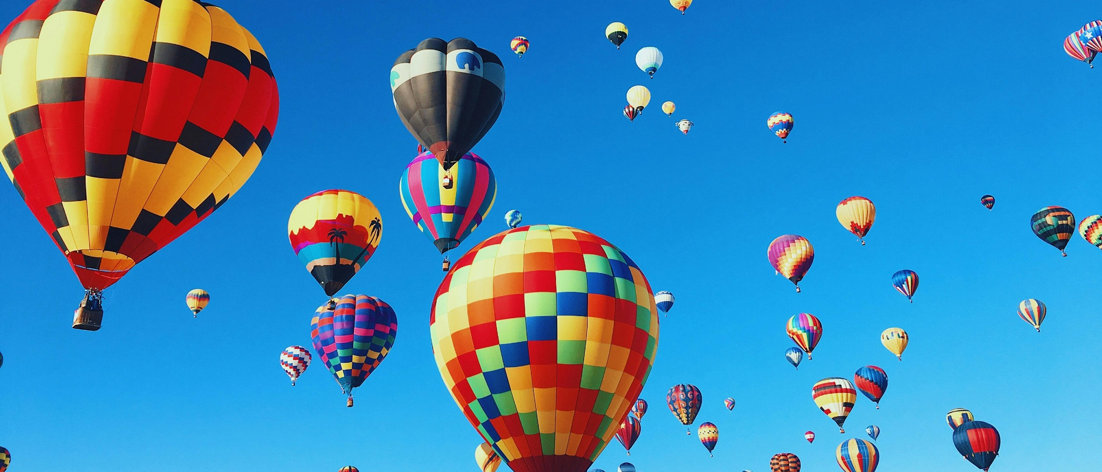 A vibrant hot air balloon festival unfolds against a clear blue sky in Albuquerque.