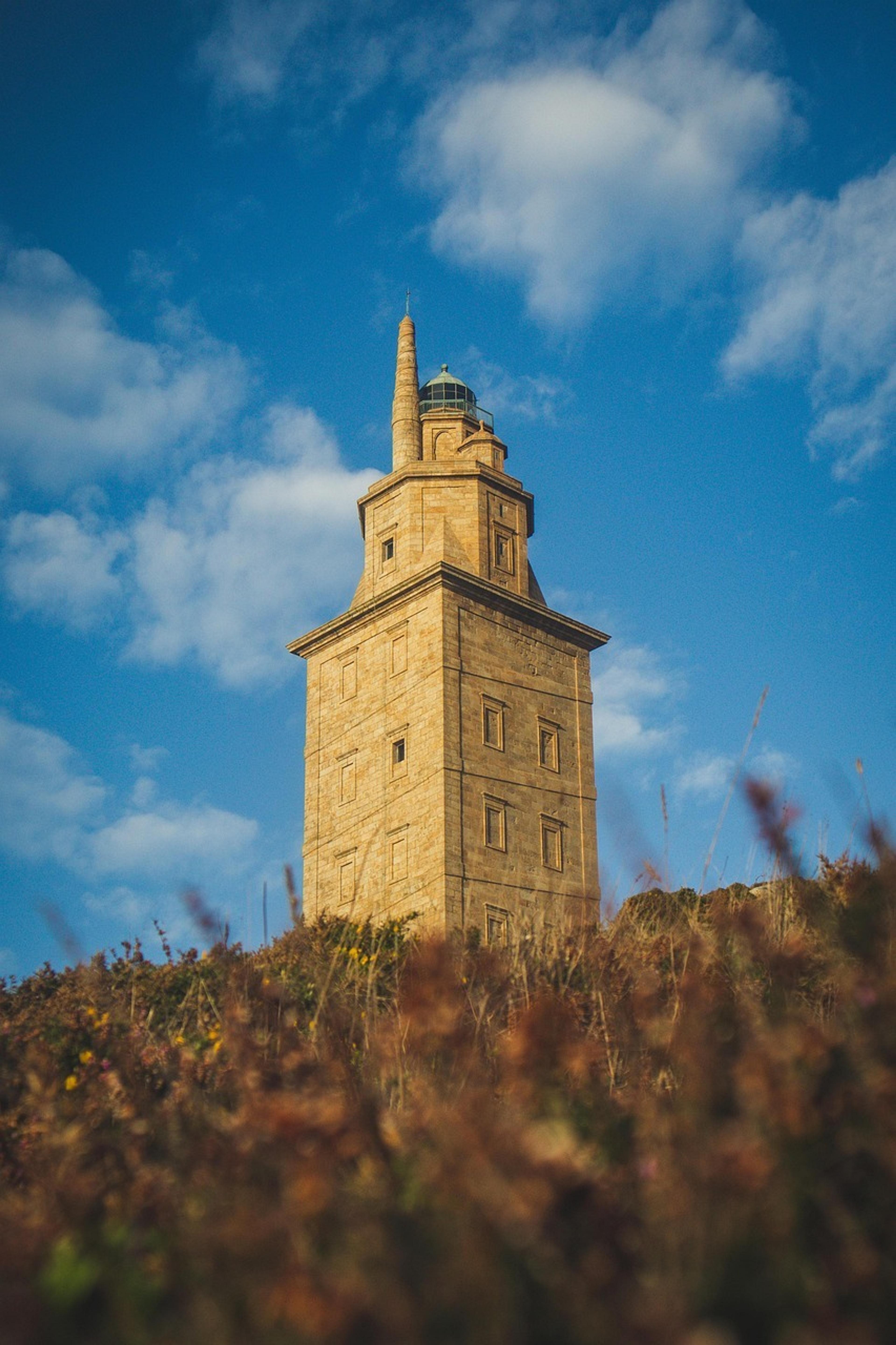 The Tower of Hercules, an ancient Roman lighthouse, stands prominently under a blue sky in A Coruña, Spain.