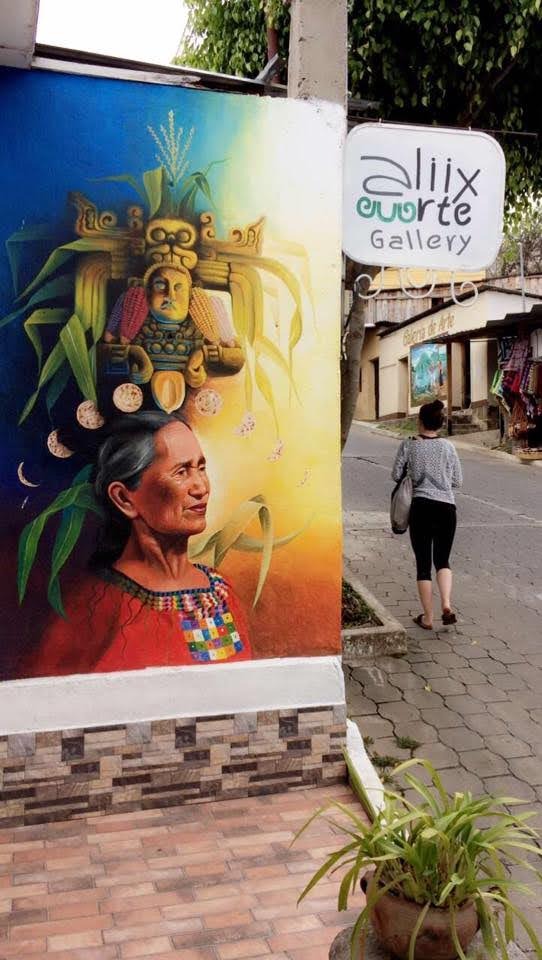 Colourful Maya art on a wall beside a cobbled street
