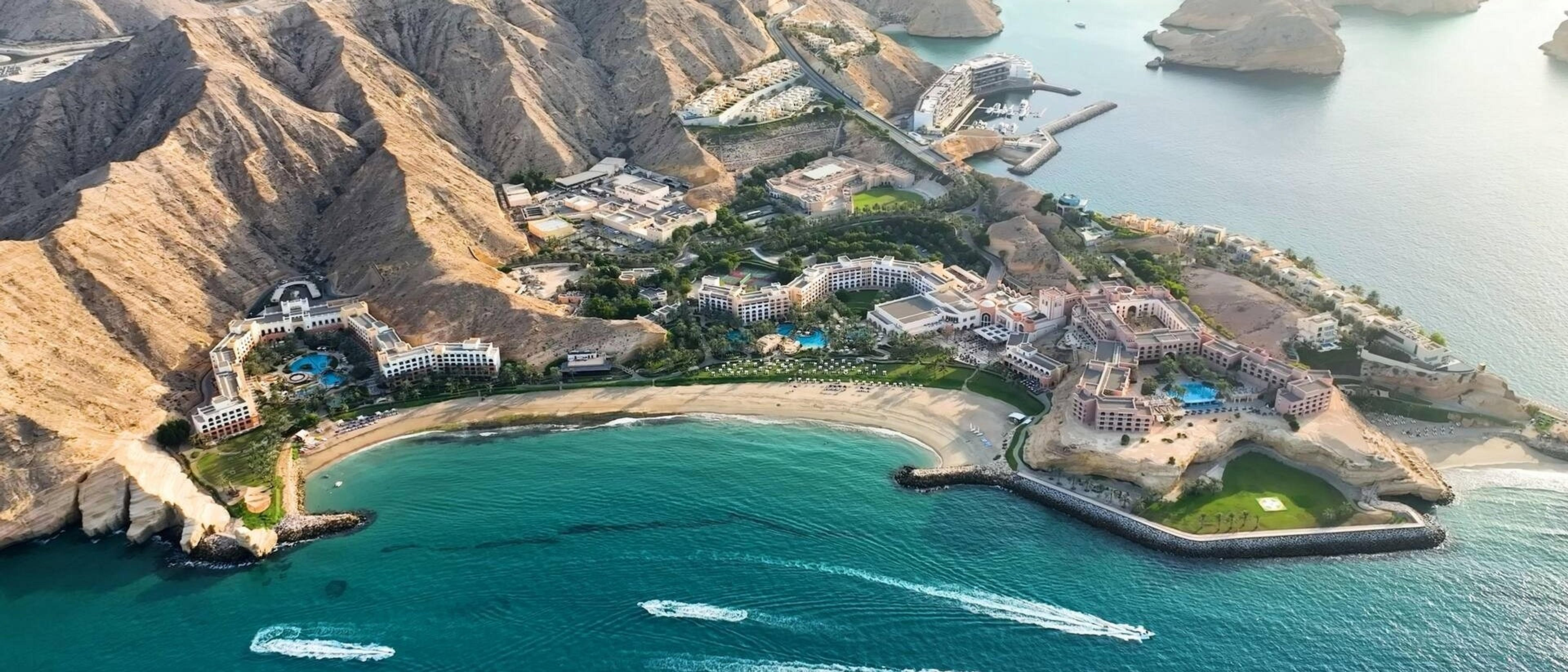 Aerial view of the Shangri-La Barr Al Jissah Resort nestled between rugged mountains and the Gulf of Oman coastline.