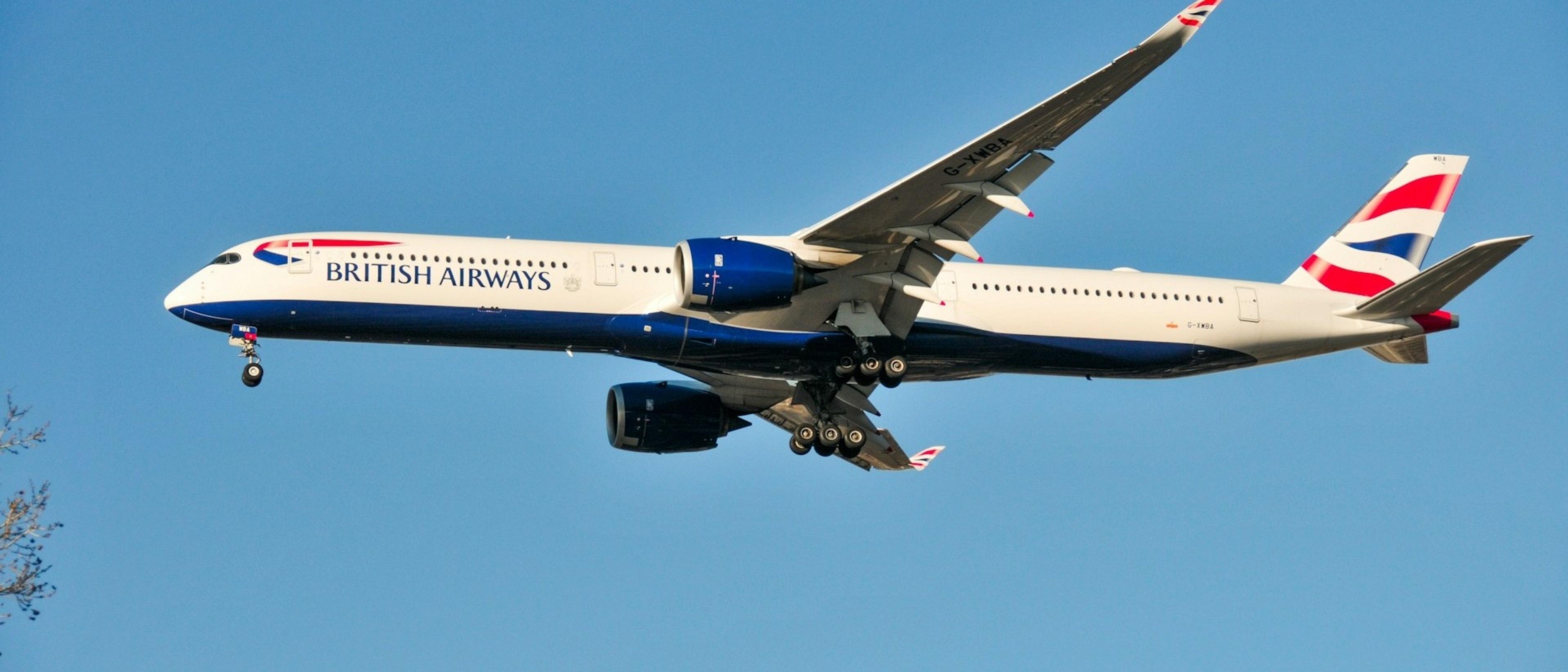 A British Airways plane is captured mid-flight against a clear blue sky, likely on approach or departure at Heathrow Airport in London.