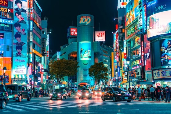 Vibrant neon lights illuminate the bustling Shibuya crossing in Tokyo, Japan.