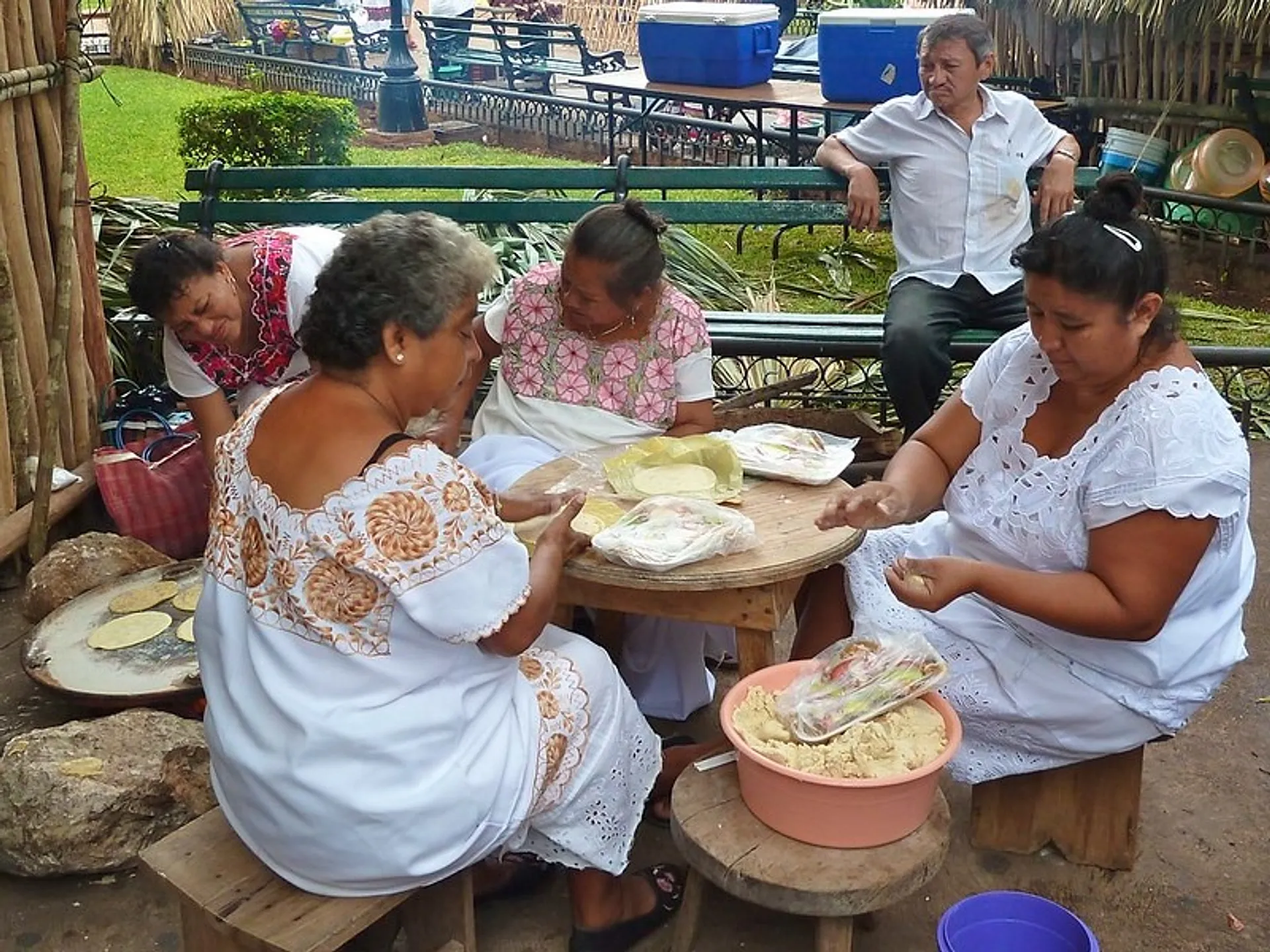 Women in traditional dresses make tortillas at a park in Mérida, Mexico.