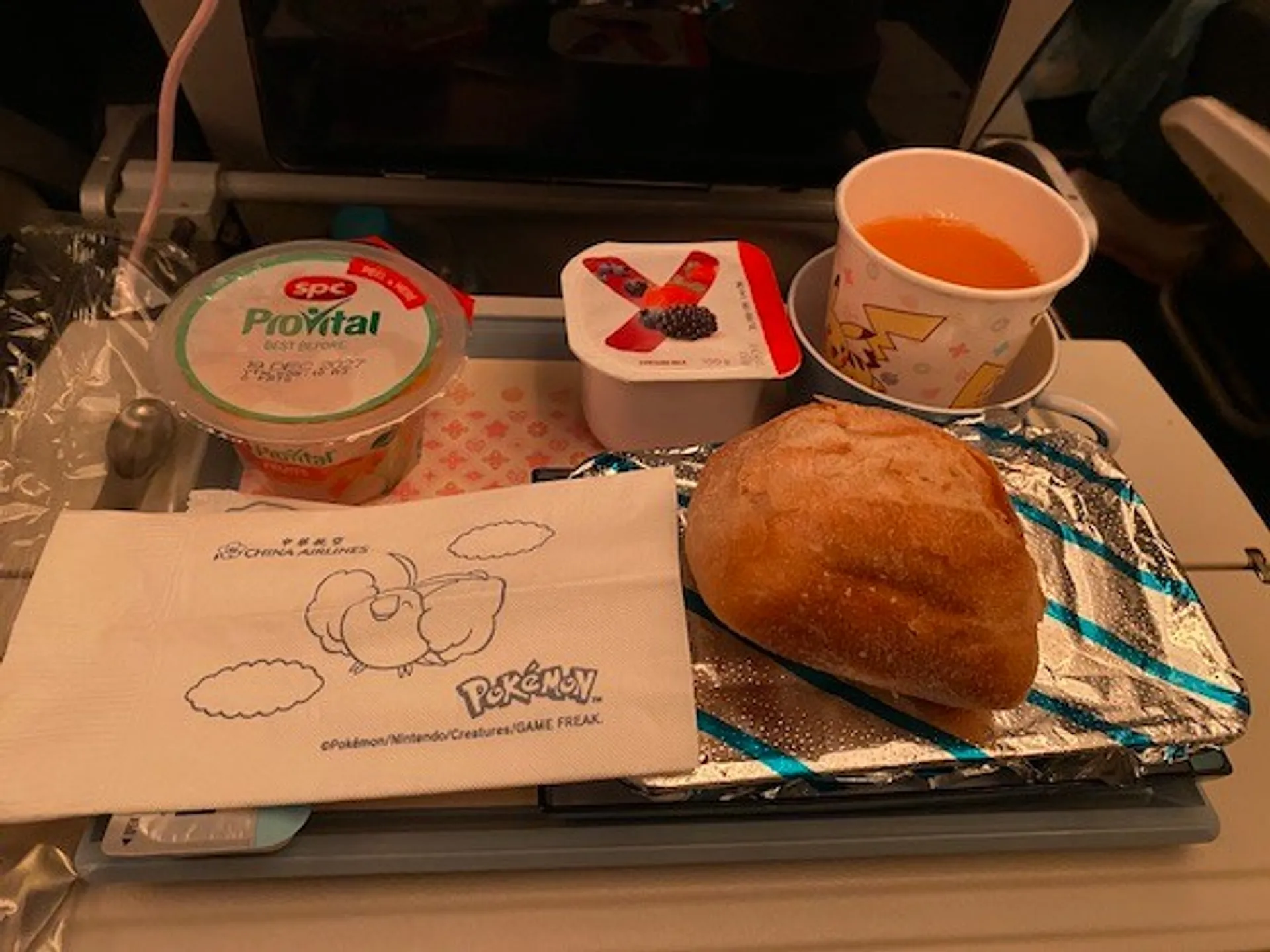 An in-flight meal on a China Airlines flight features a variety of packaged foods and a cup with a Pikachu design.