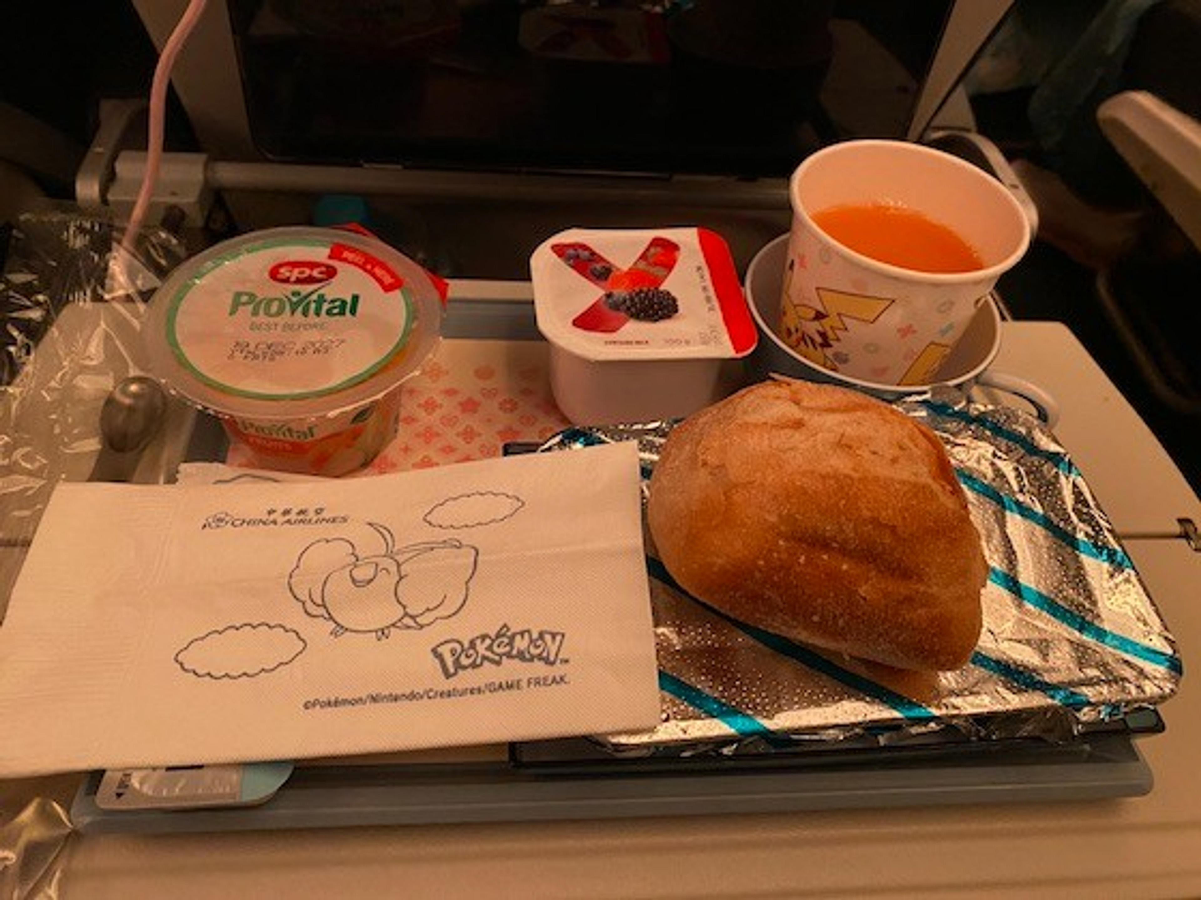 An in-flight meal on a China Airlines flight features a variety of packaged foods and a cup with a Pikachu design.