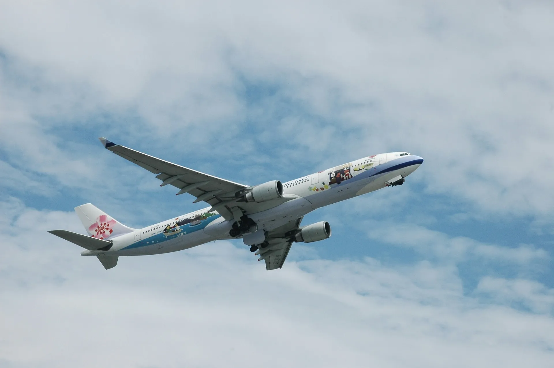 An China Airlines plane featuring a Hello Kitty design ascends under a partly cloudy sky.