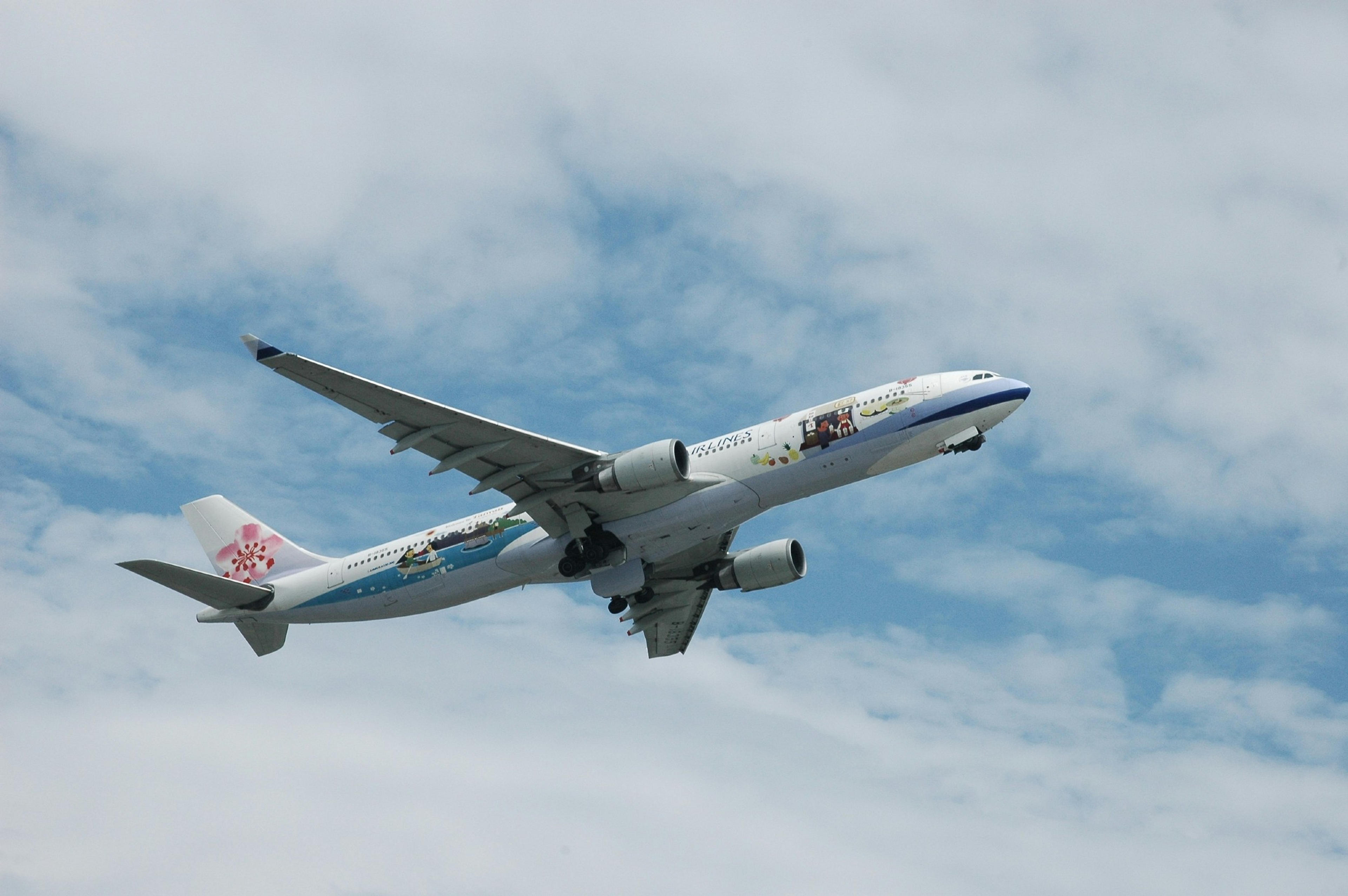 An China Airlines plane featuring a Hello Kitty design ascends under a partly cloudy sky.