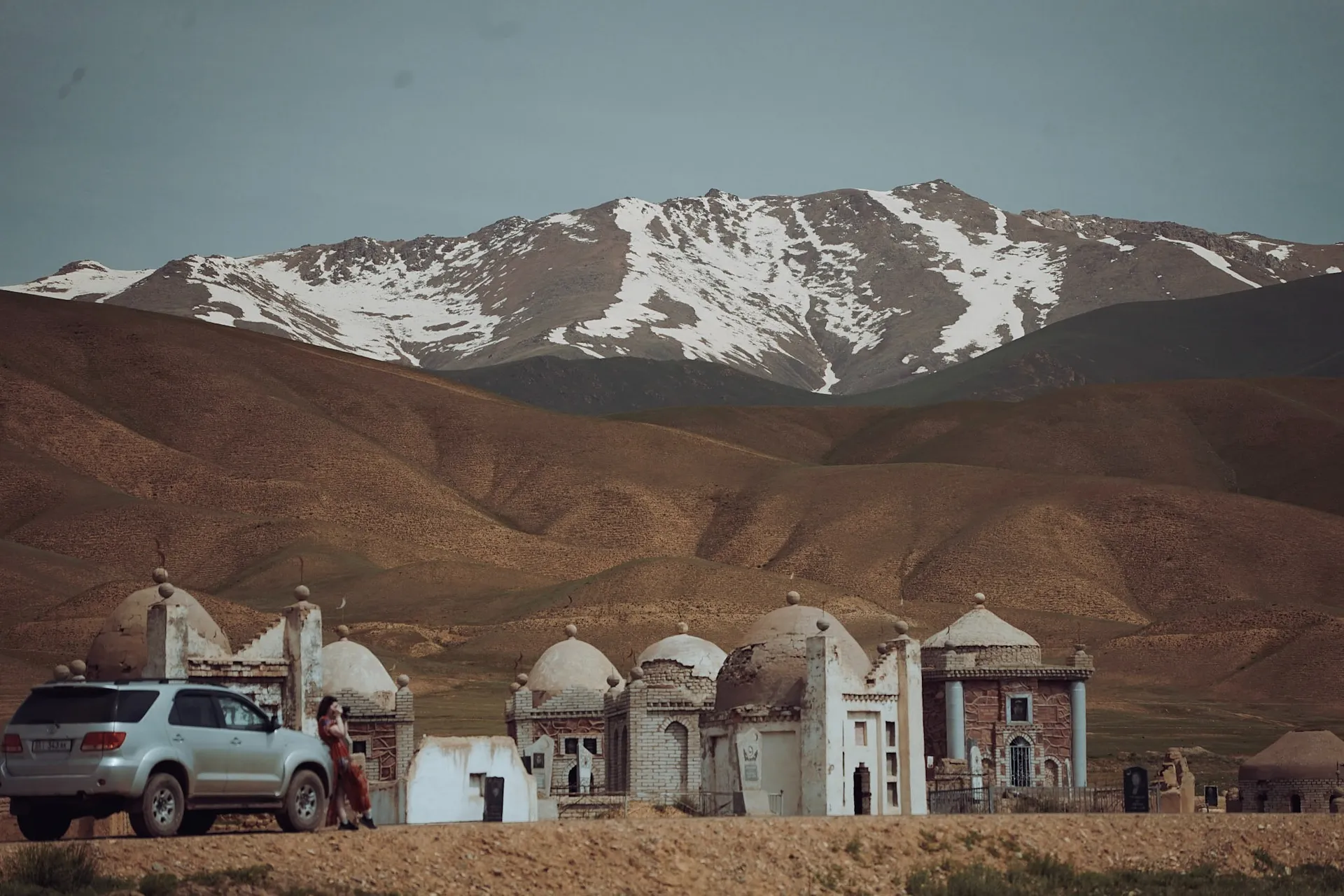 Snow-capped mountains rise in the backdrop of a remote village in Kyrgyzstan.