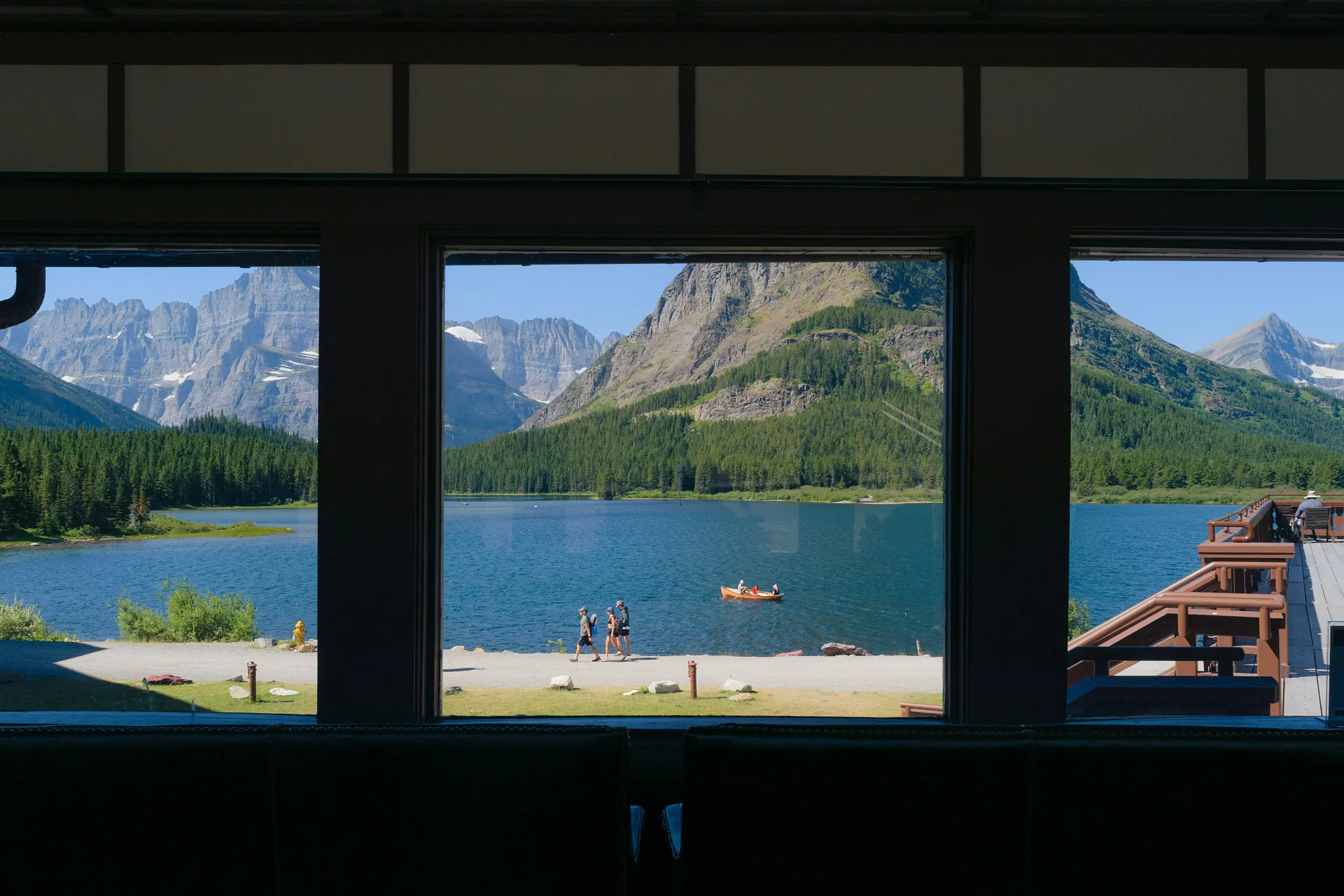 A serene view of Swiftcurrent Lake and surrounding mountains from a window in Glacier National Park, Montana.