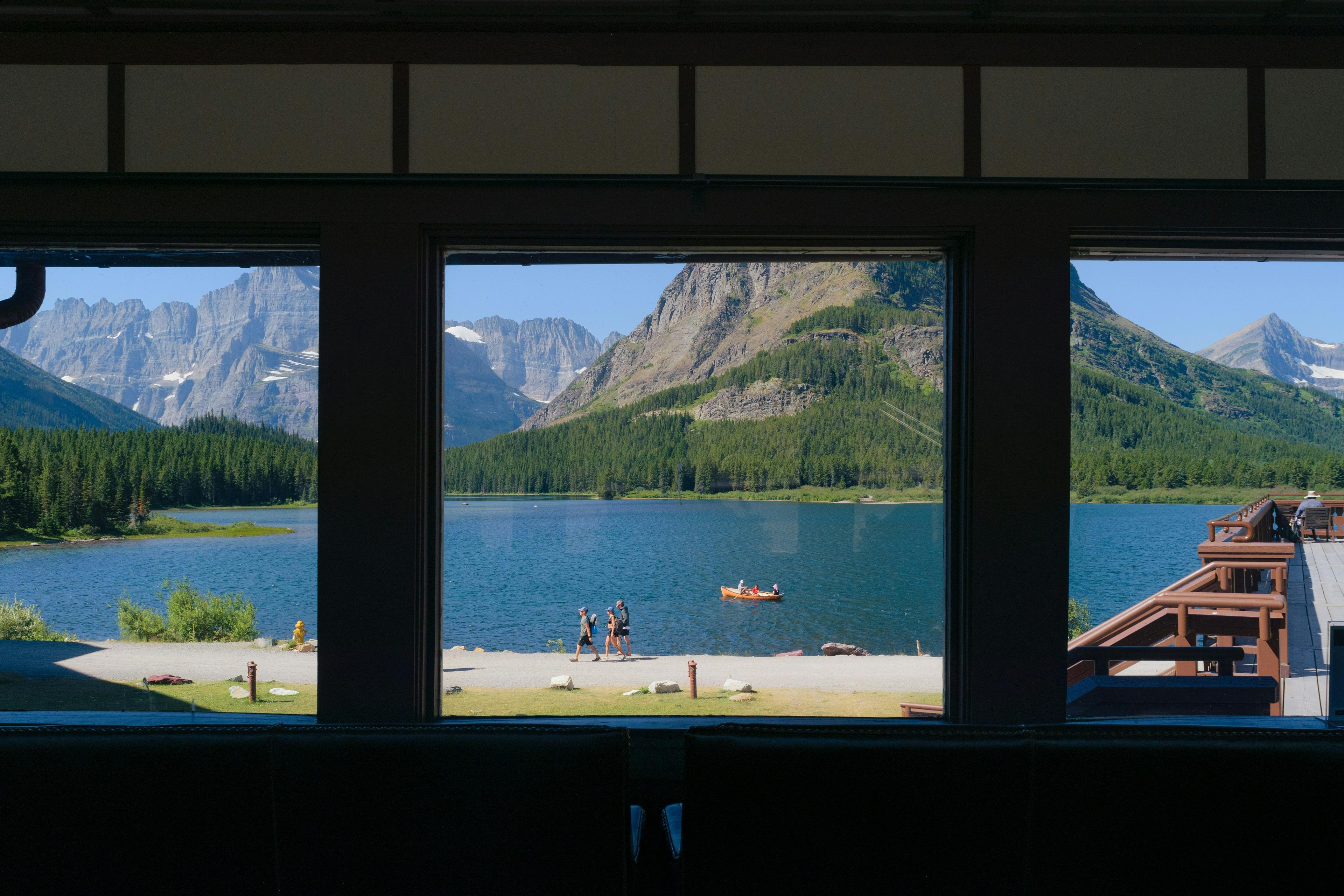 A serene view of Swiftcurrent Lake and surrounding mountains from a window in Glacier National Park, Montana.