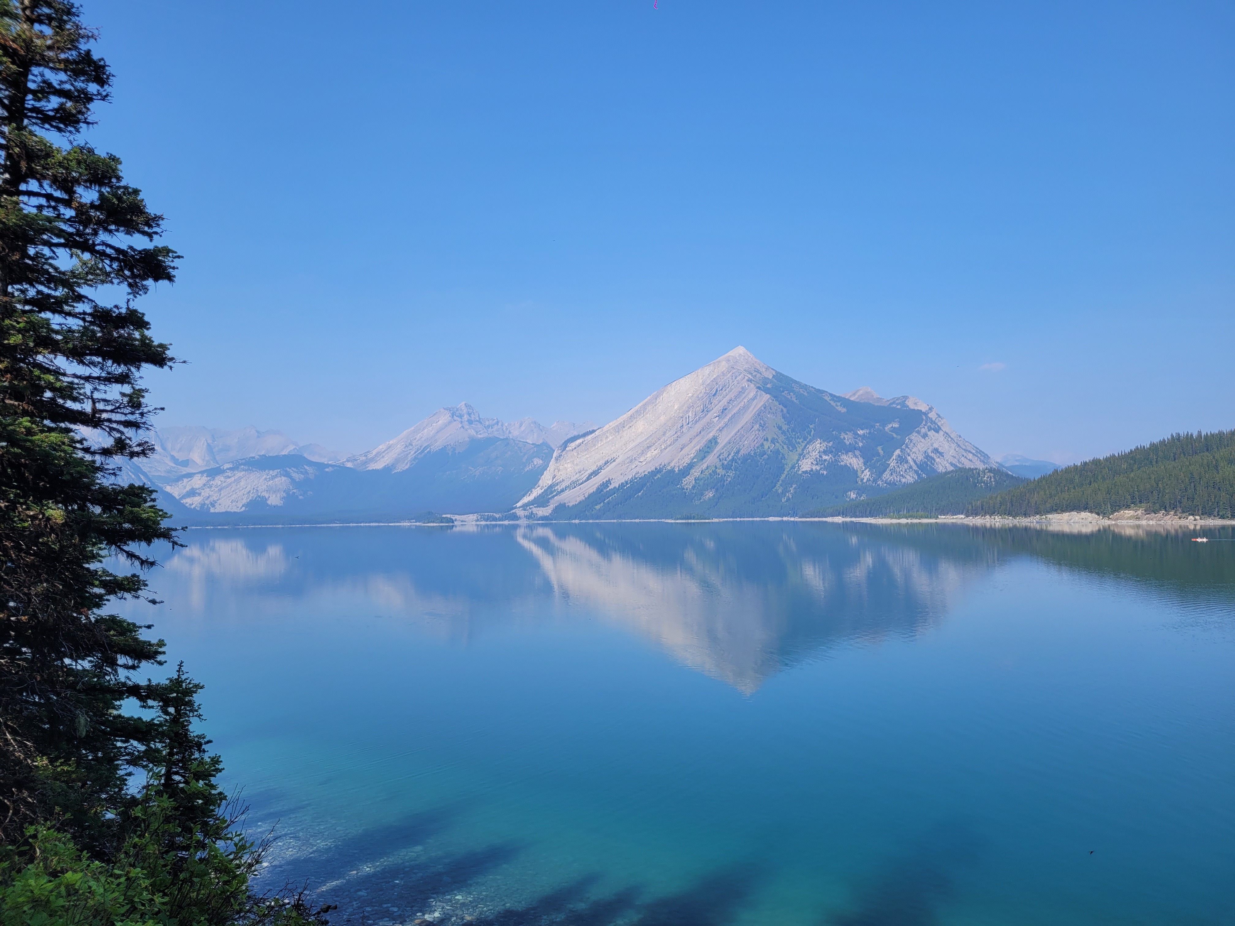 A serene view of Upper Kananaskis Lake in Alberta, Canada, with majestic mountains reflecting on the tranquil water.