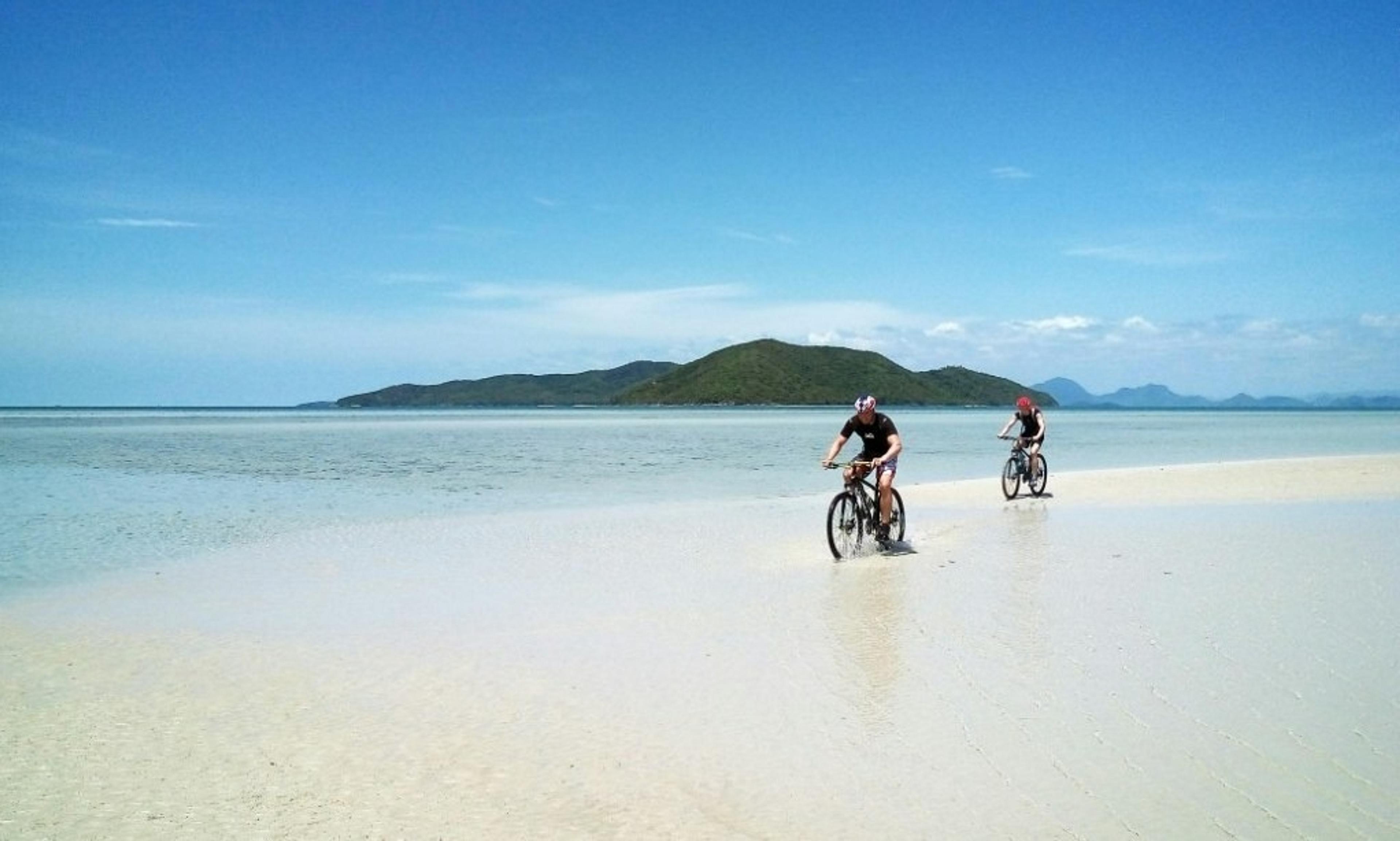 People riding bicycles on the beach