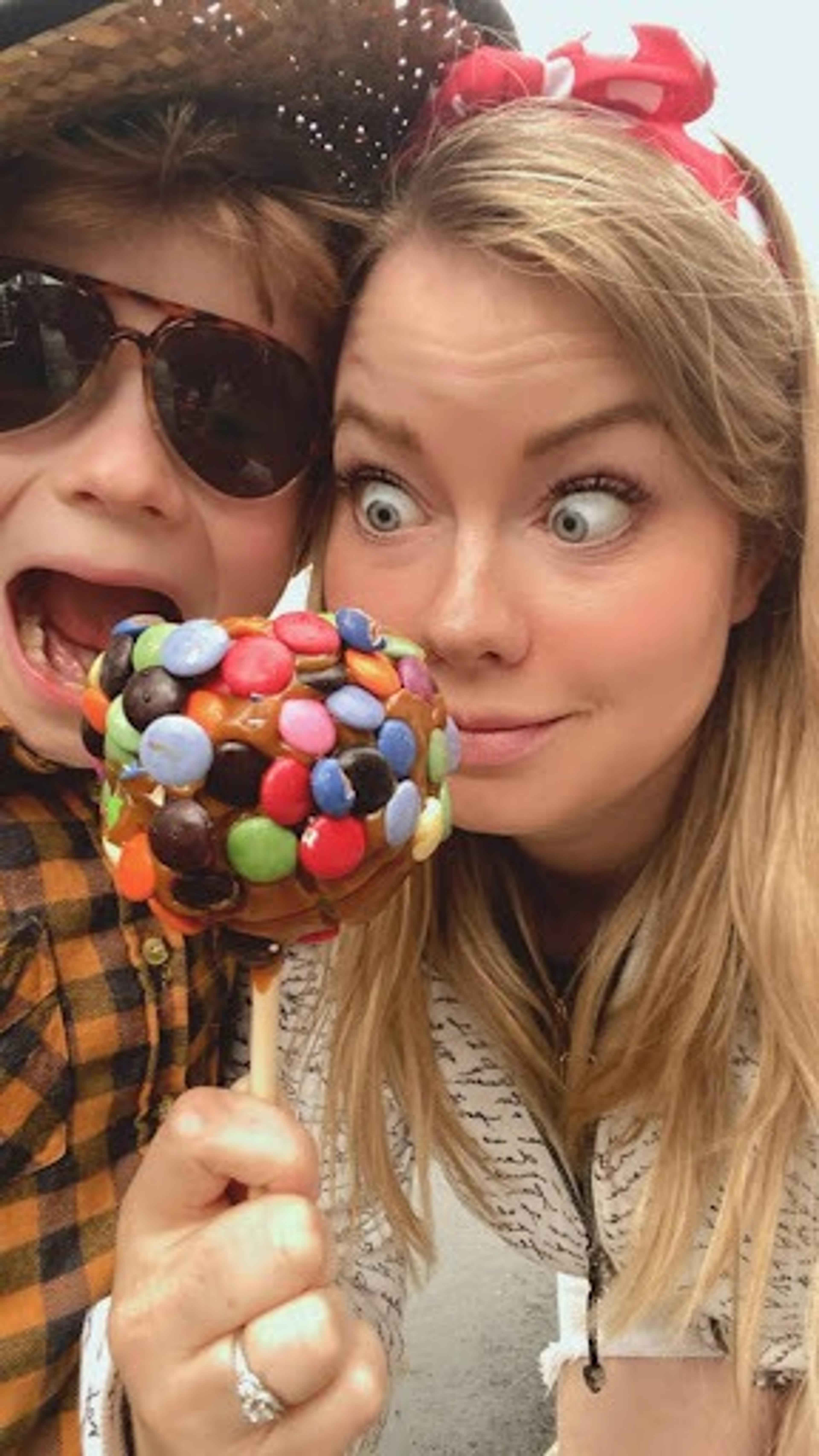 Kristi and her son bite into a candy apple