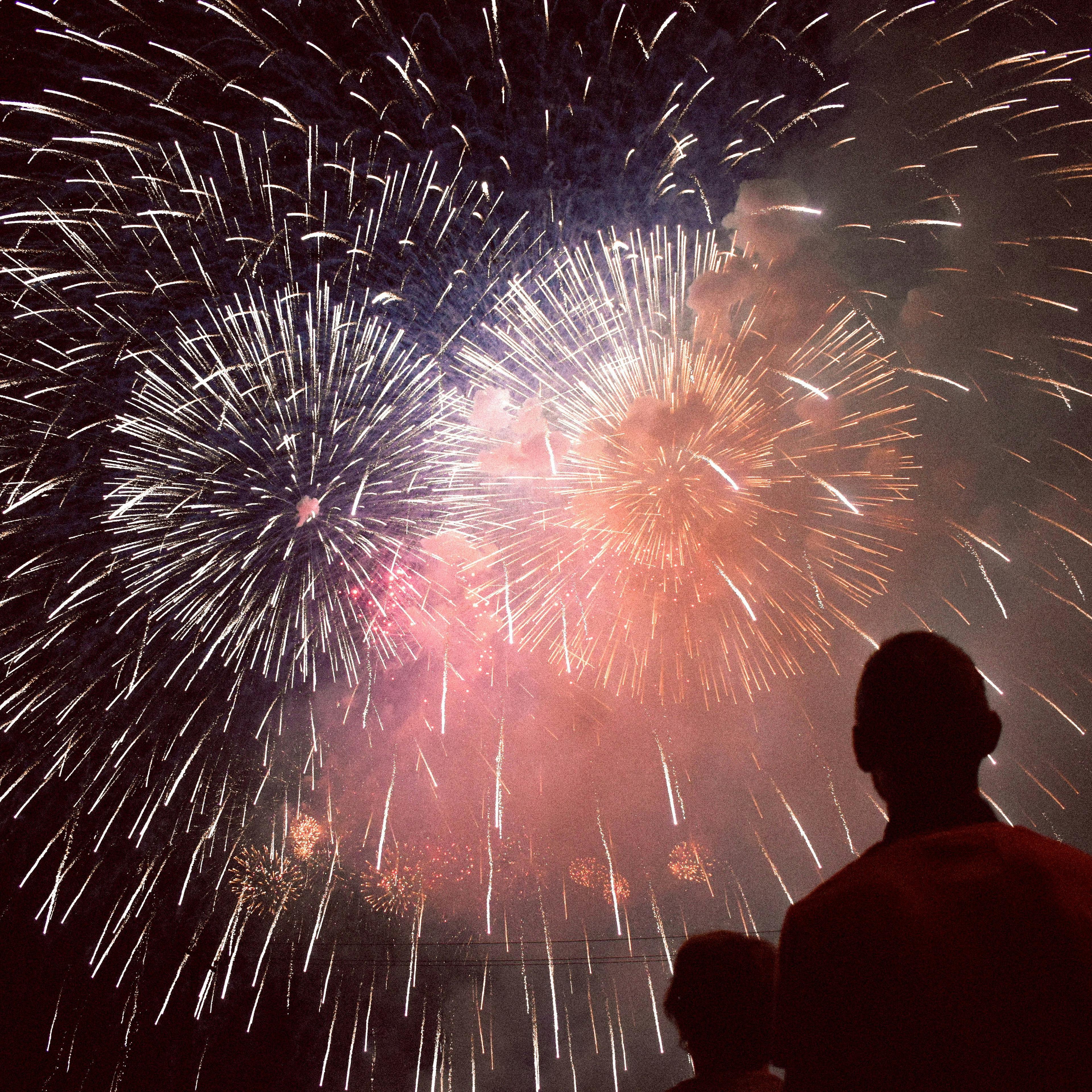 Father and son watching fireworks explode above them.