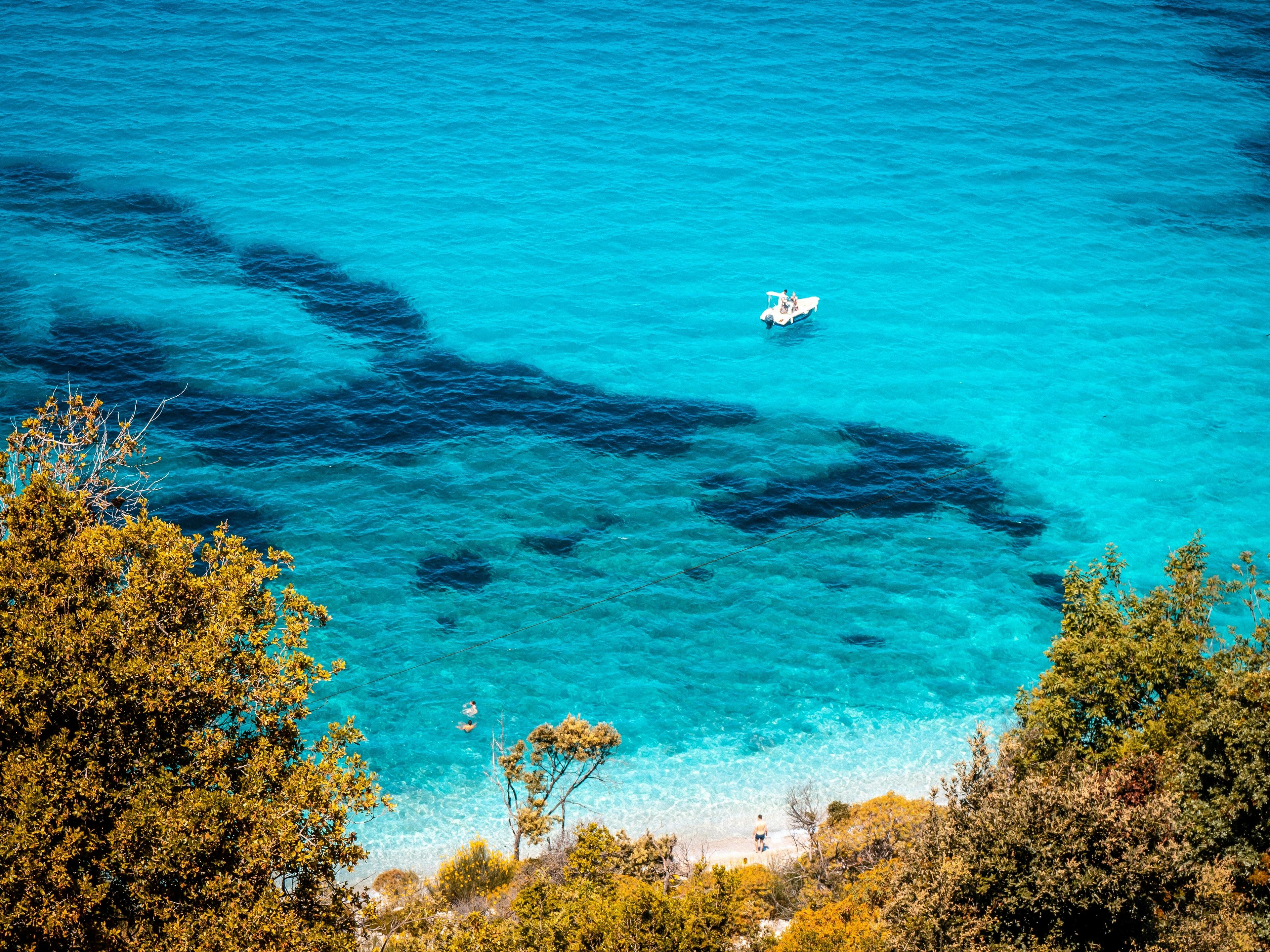 Crystal-clear turquoise waters and vibrant flora surround the serene coastline of Albania.