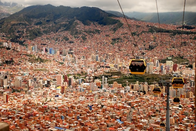La Paz, Bolivia sprawls below with cable cars traversing above the vibrant cityscape and mountains in the distance.