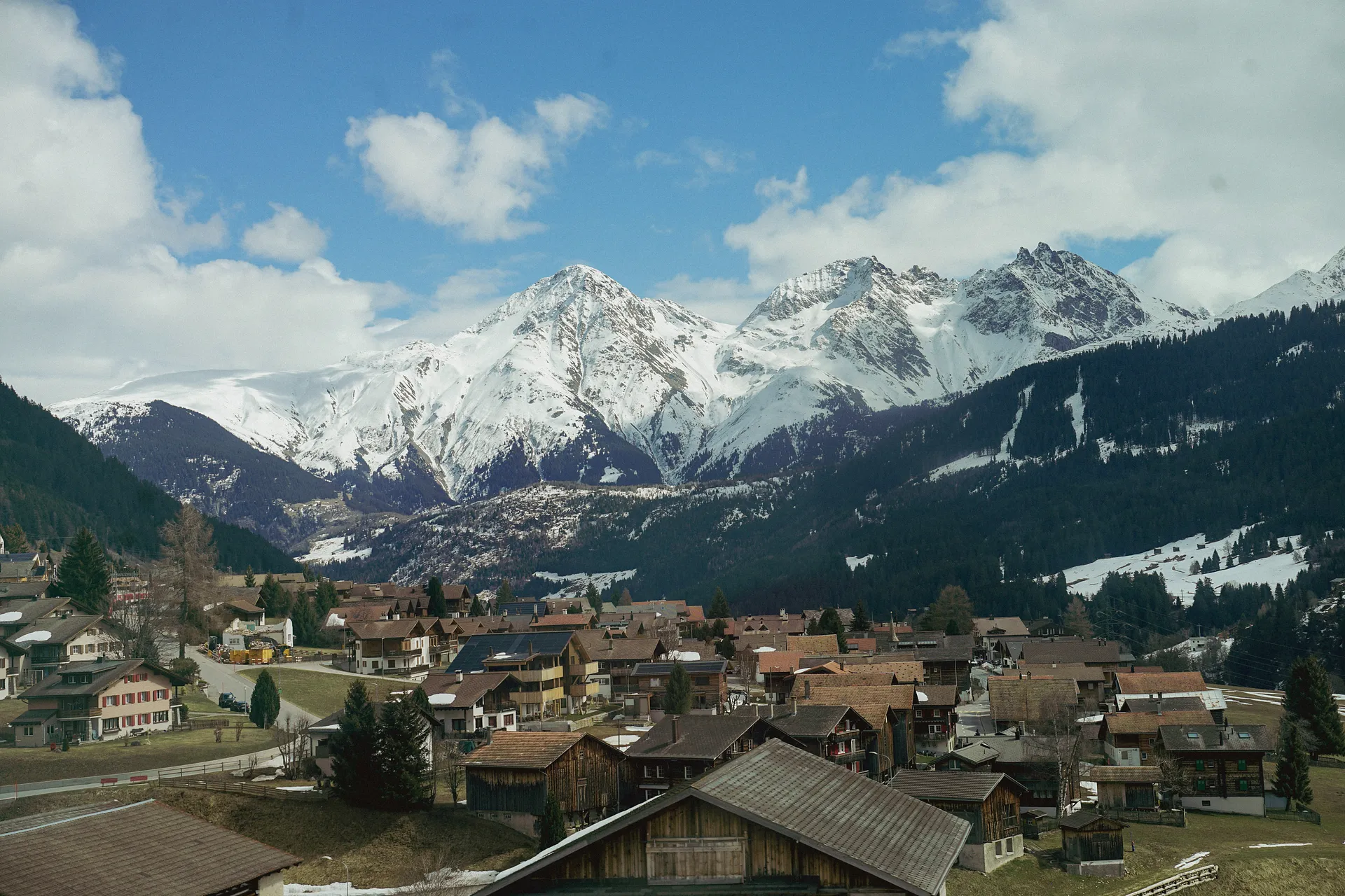 A picturesque village nestled in the Swiss Alps offers a stunning view of snow-capped mountains.
