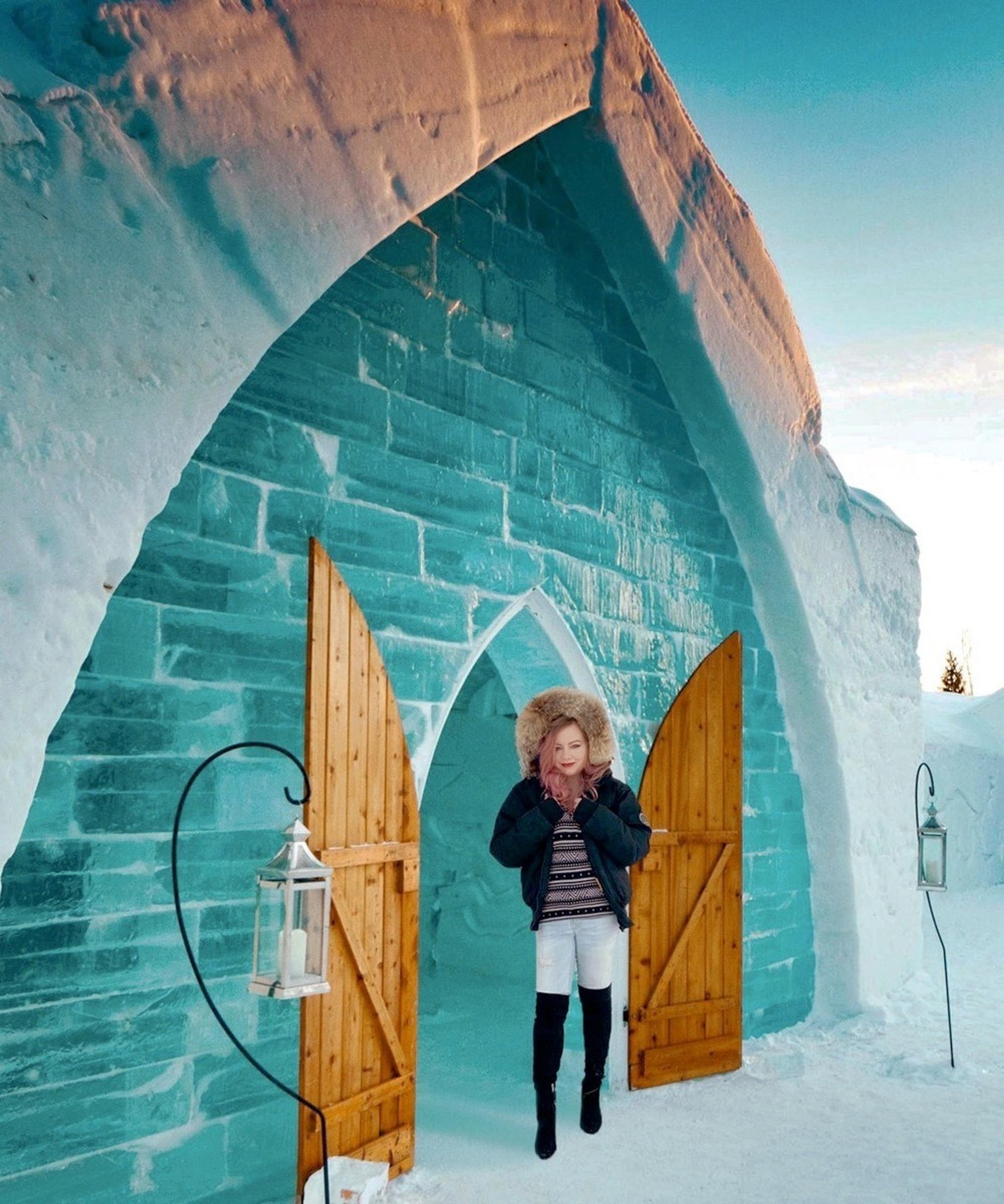 Woman standing outside of a hotel sculpted of snow and ice.