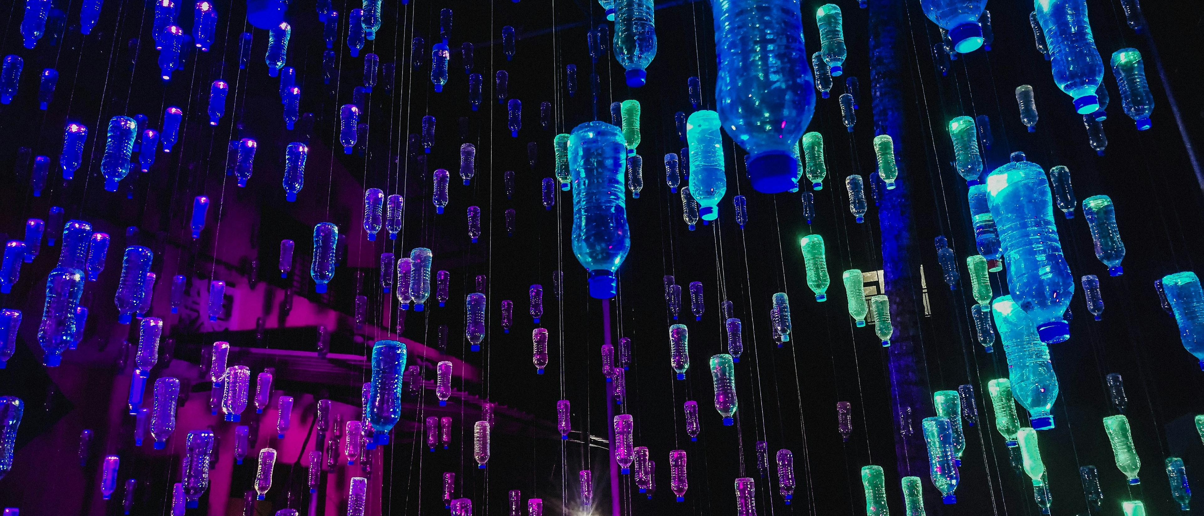 A creative art installation featuring illuminated plastic bottles in vibrant blue and purple