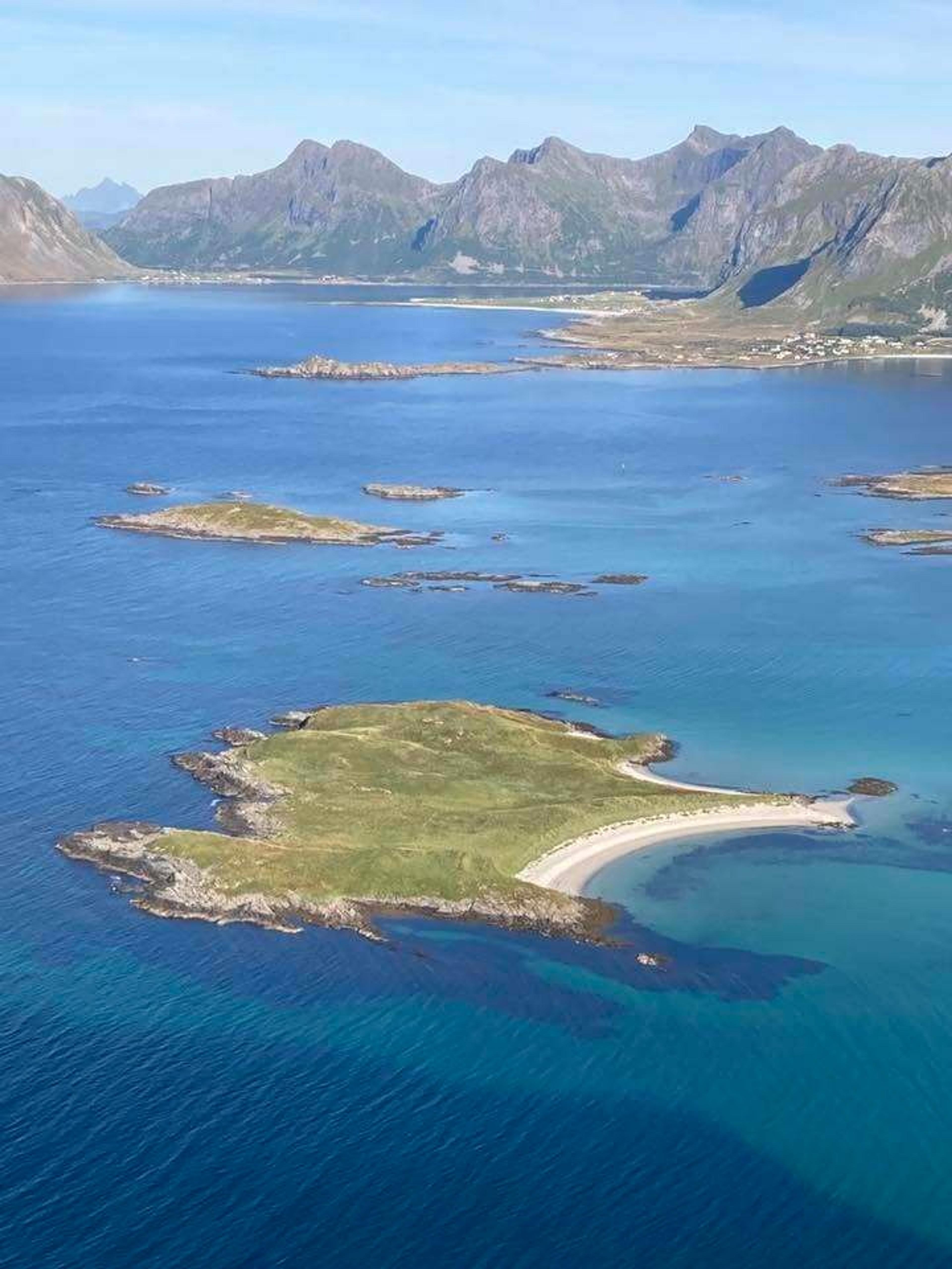 Aerial view of the picturesque coastline and islands of Lofoten, Norway, with majestic mountains in the background.