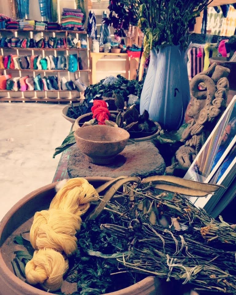Fabrics being dyed in wooden bowls full of leaves