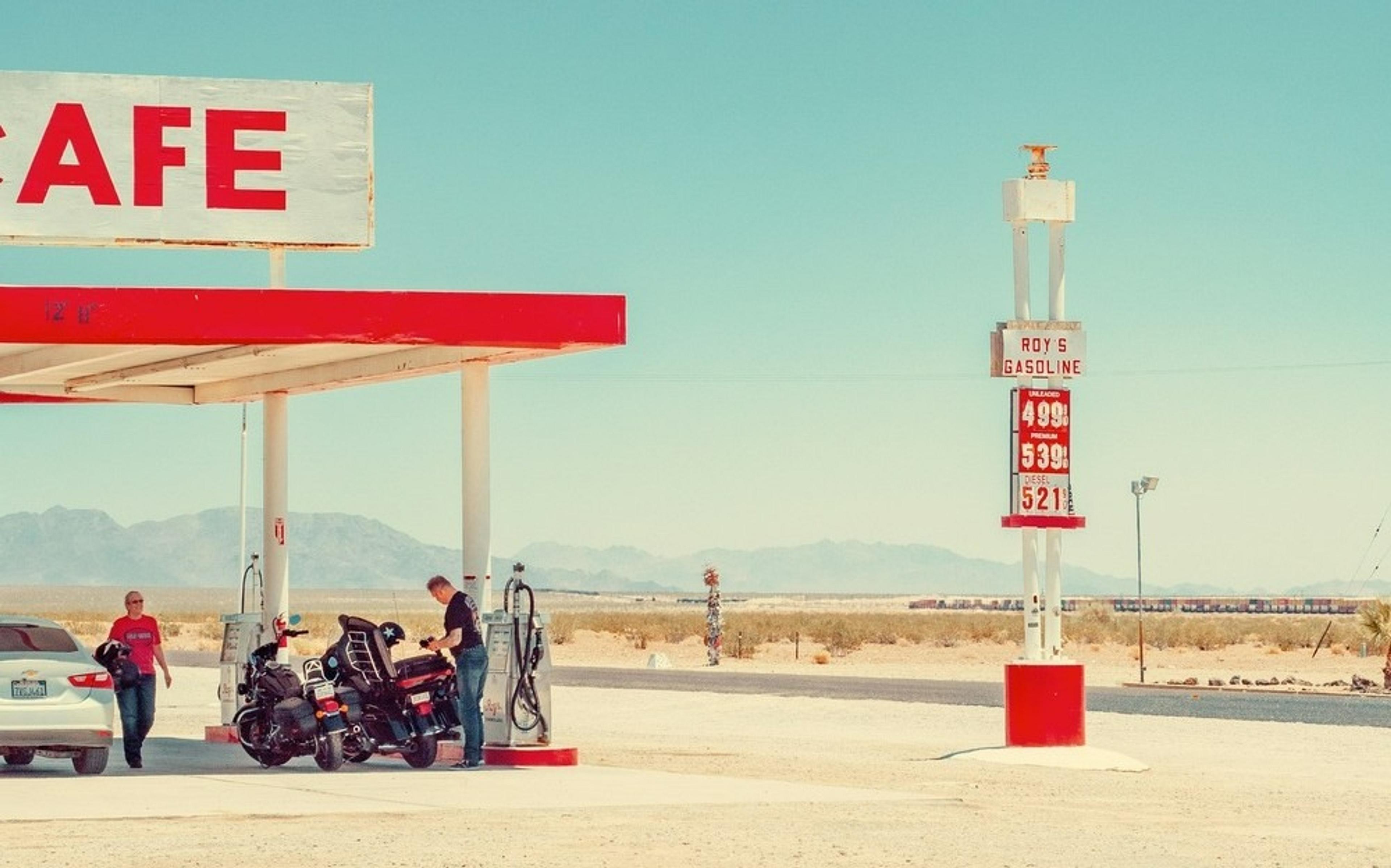Motorcycles and a car are parked at Roy's Motel and Café, a historic Route 66 location in Amboy, California, against a desert backdrop.