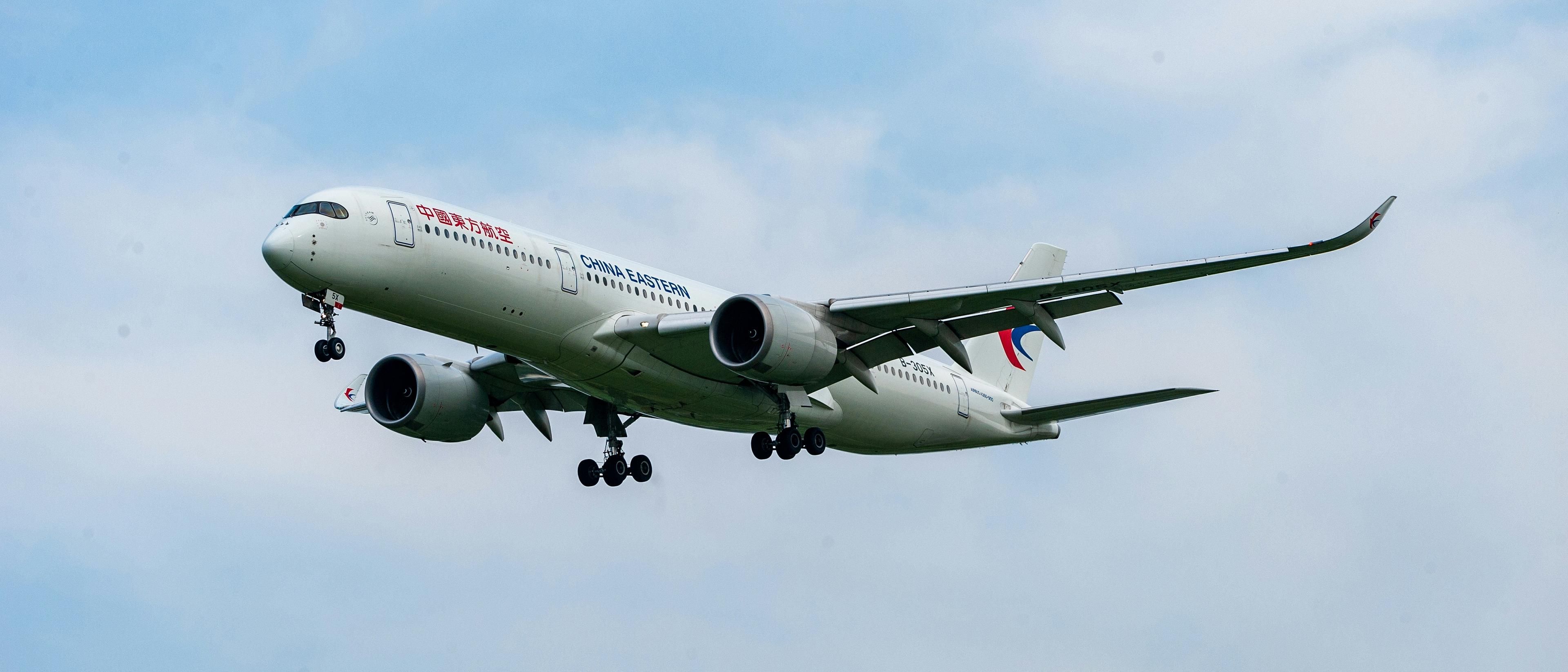 A China Eastern Airlines airplane is descending against a cloudy sky.
