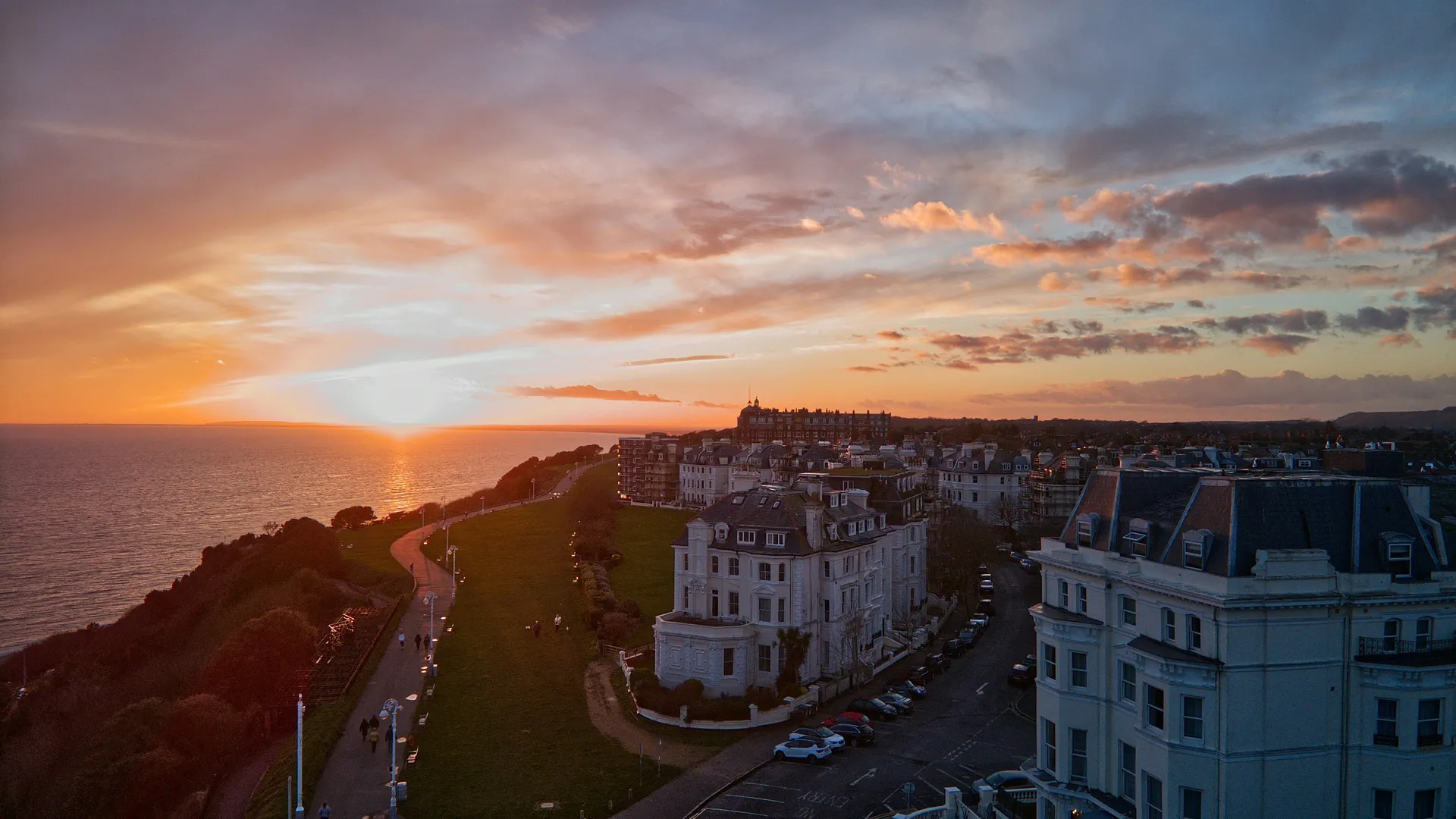 A stunning sunset illuminates the coastline and historic buildings of The Leas in Folkestone, United Kingdom.