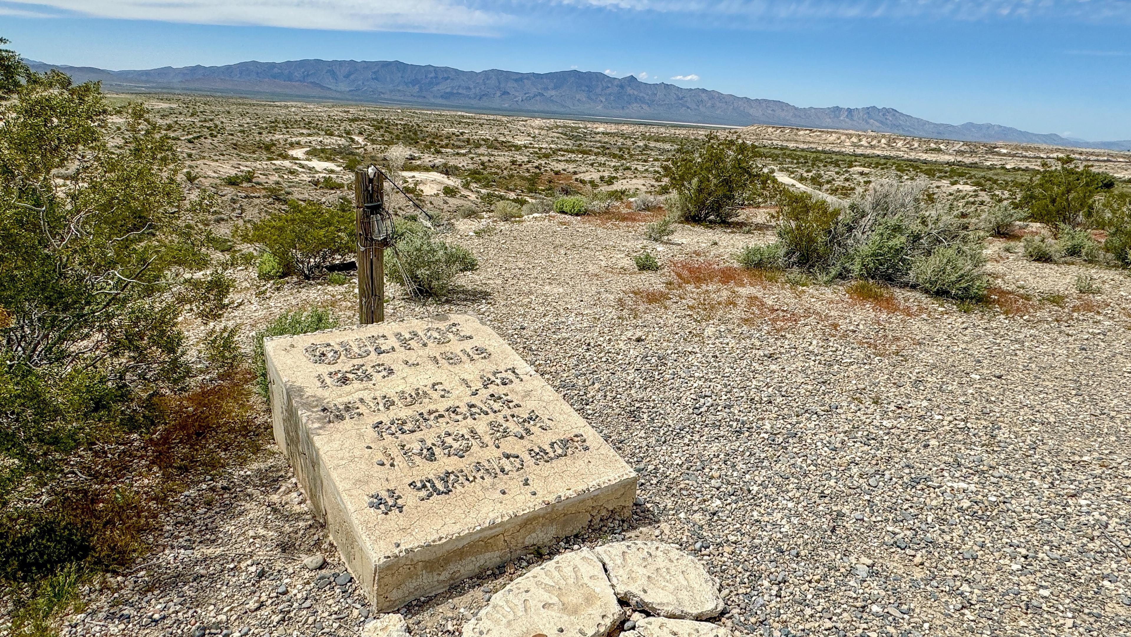 A handmade grave marker sits at the top of a desert canyon