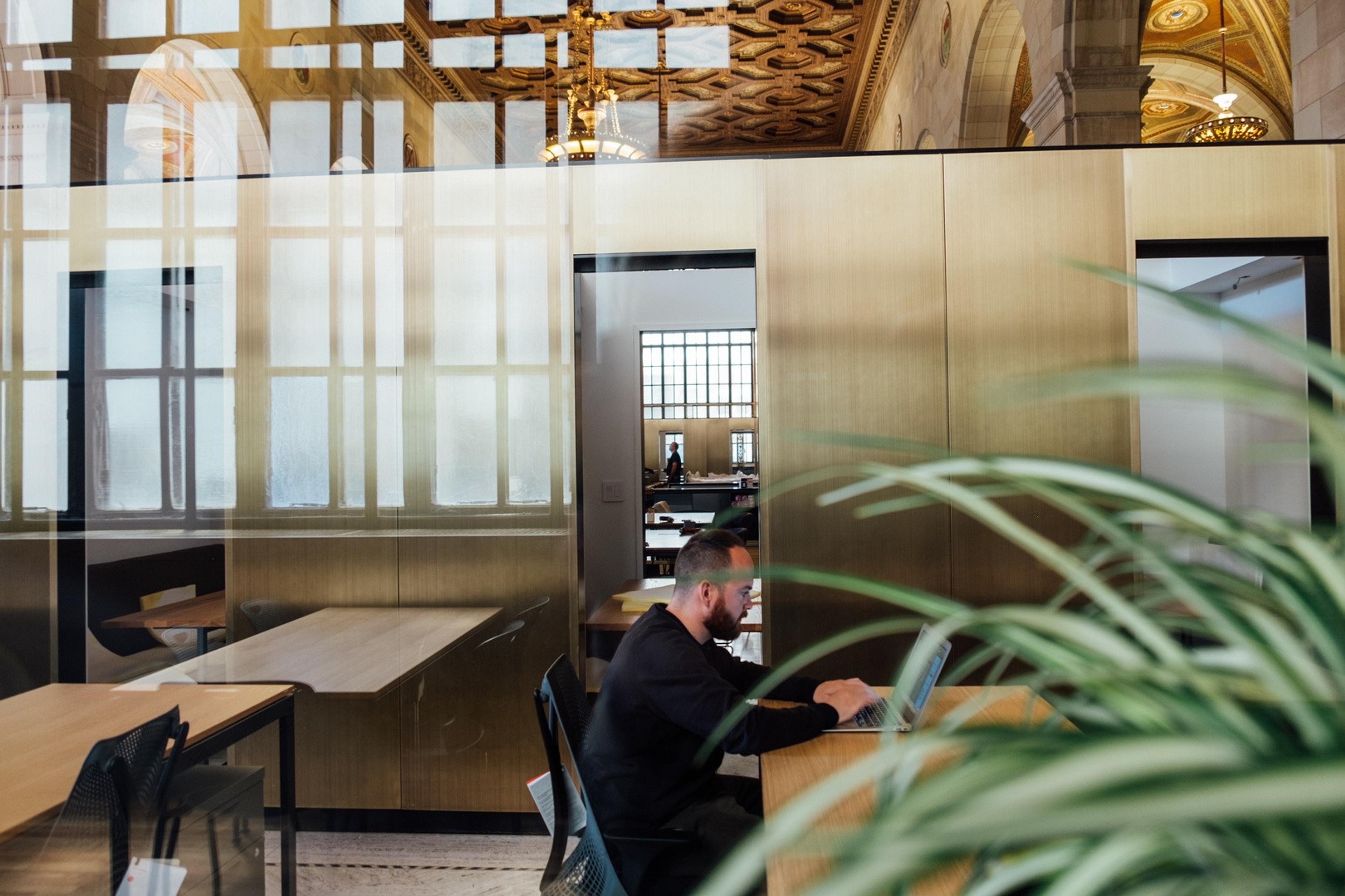 A man works on his laptop inside a public library.