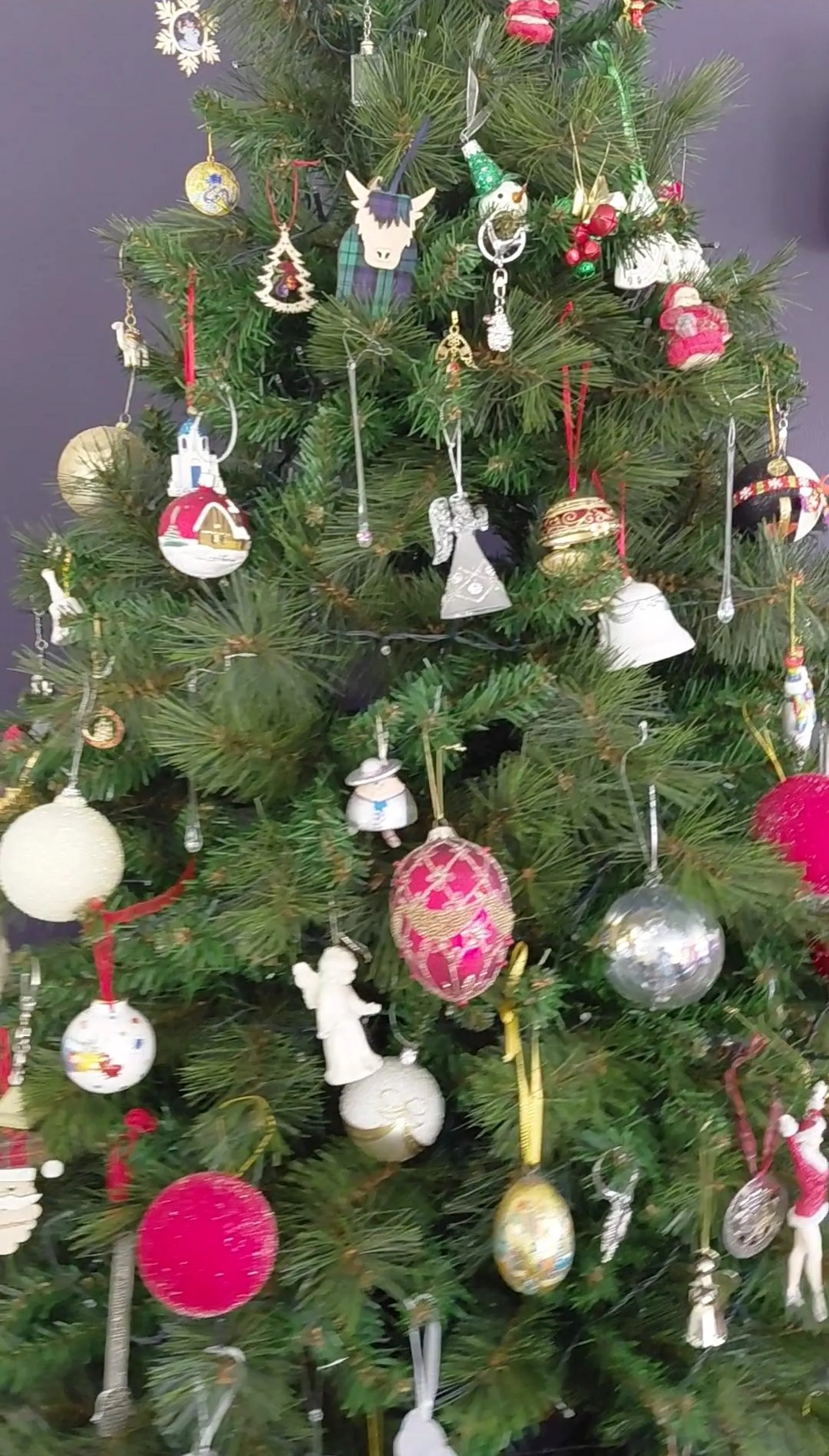 A Christmas tree adorned with diverse ornaments stands, possibly in a festive setting in Edinburgh, Scotland.