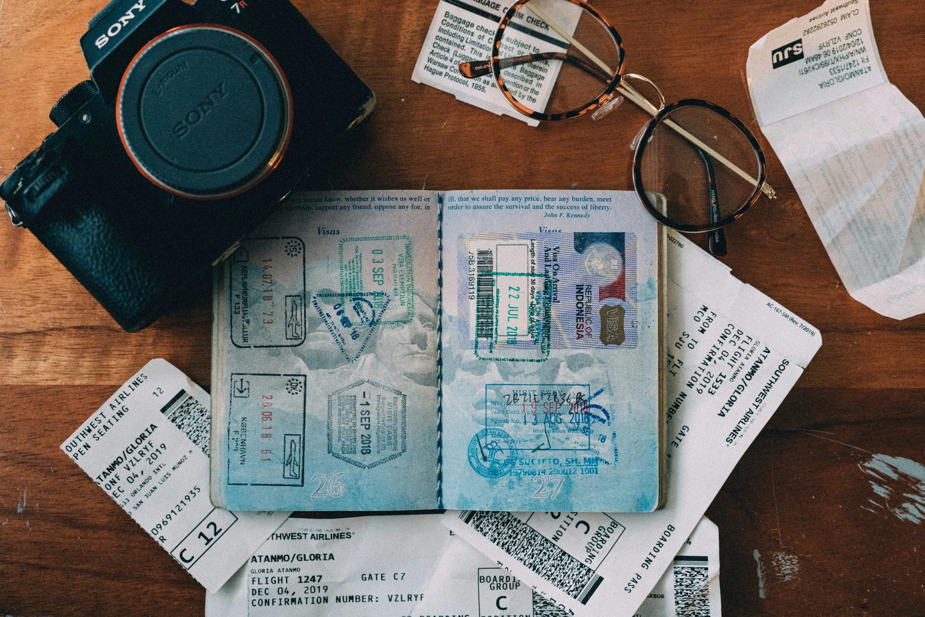 A travel-themed arrangement featuring a camera, glasses, and a passport with stamps from Indonesia, alongside boarding passes for a flight from Surabaya on Southwest Airlines.