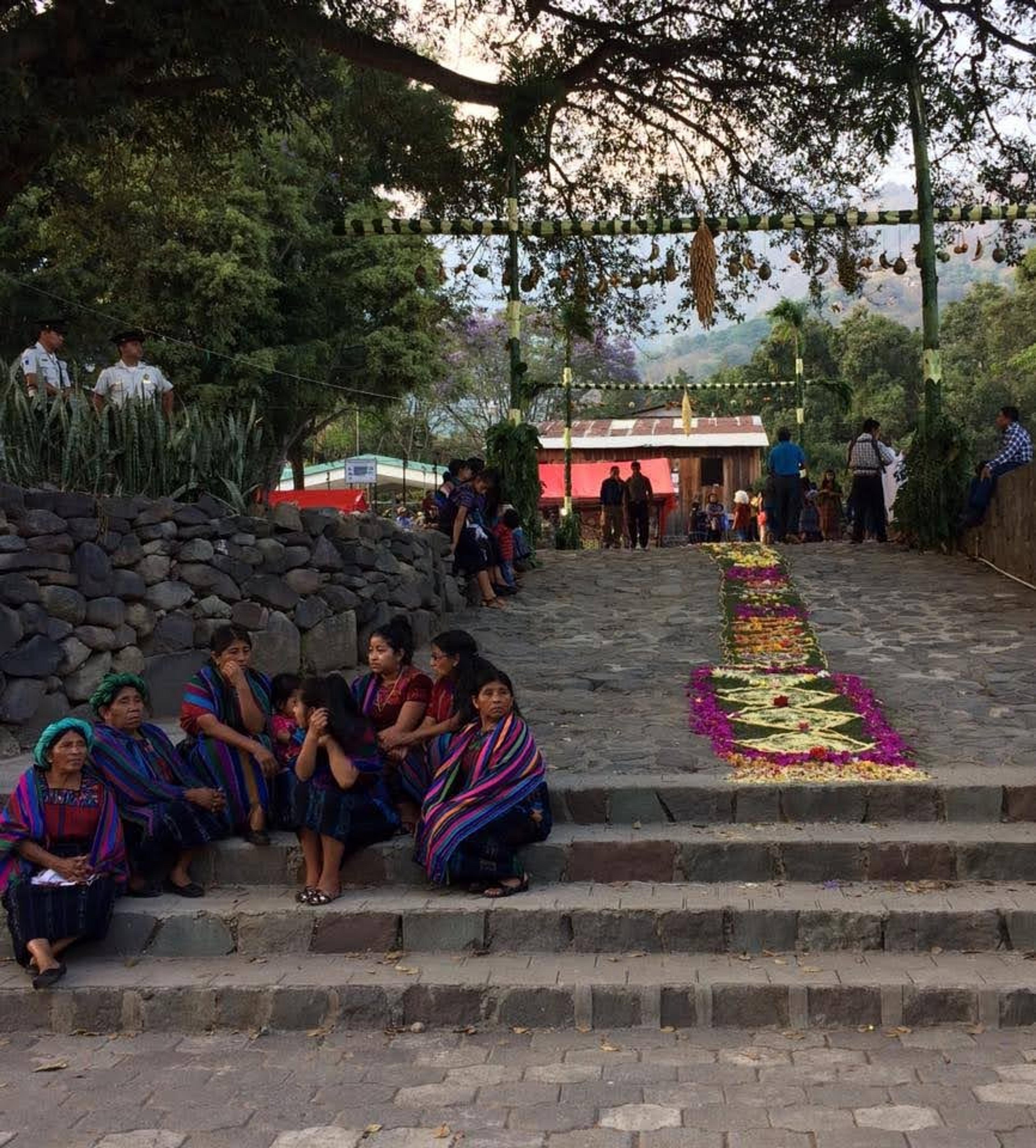 Visitors and locals gather at the Santo Tomás Church in Chichicastenango, Guatemala, surrounded by vibrant textiles and floral arrangements.
