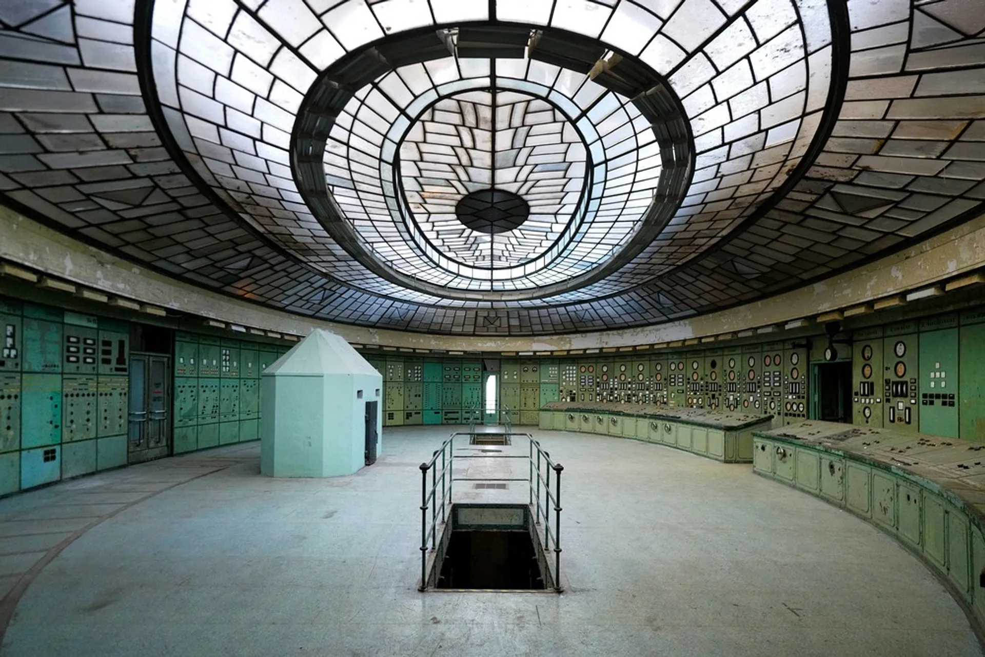 An abandoned control room with vintage equipment and a large stained glass ceiling.