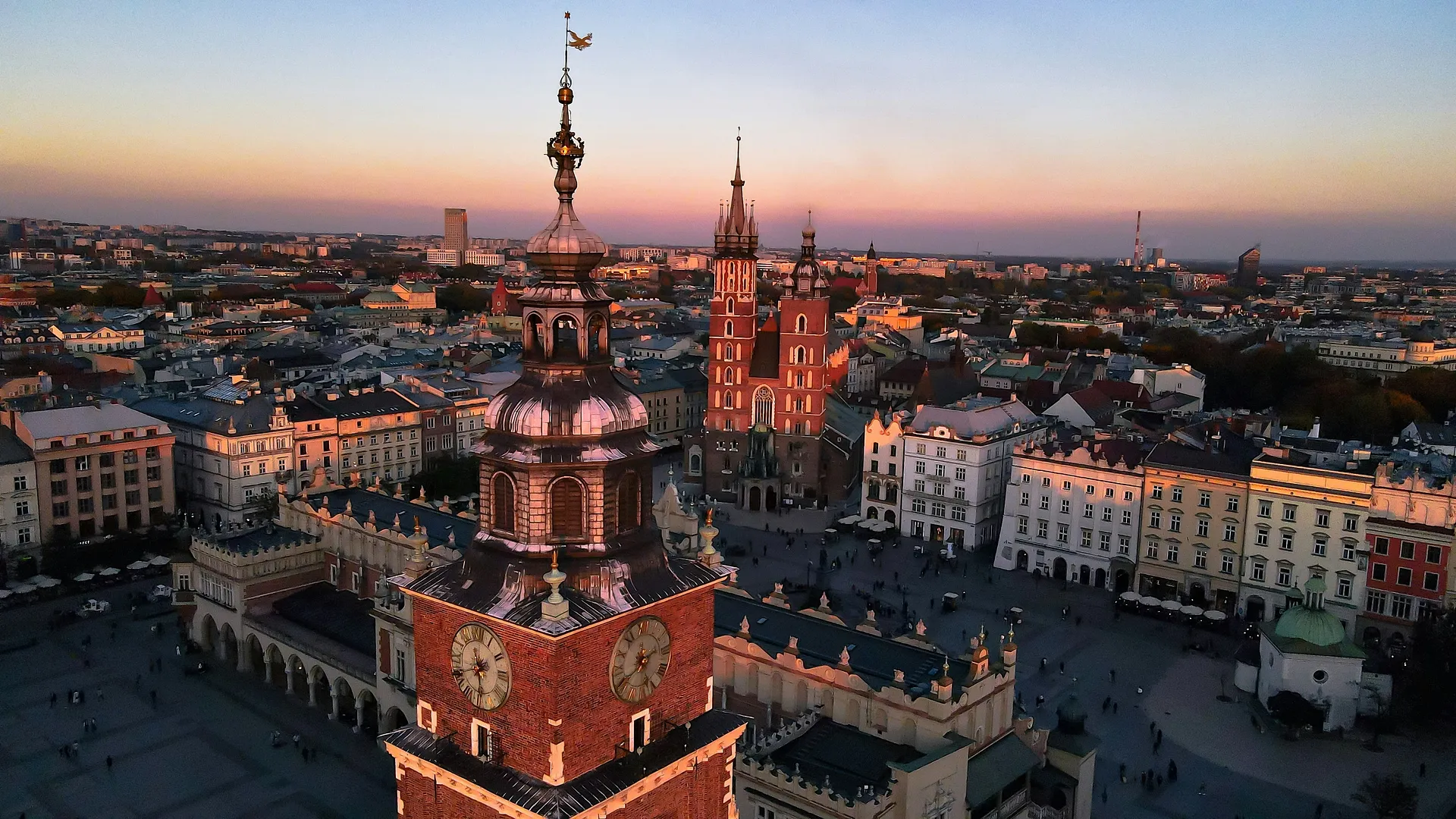Aerial view of Kraków's Main Market Square at sunset, featuring St. Mary's Basilica and the Cloth Hall.