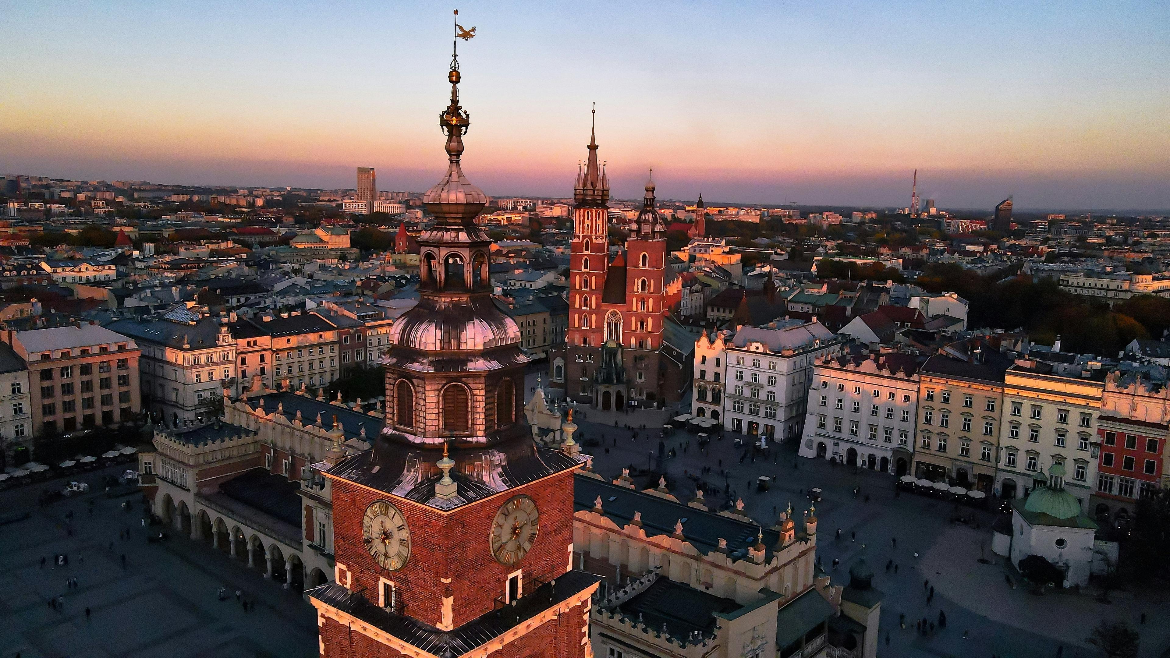 Aerial view of Kraków's Main Market Square at sunset, featuring St. Mary's Basilica and the Cloth Hall.
