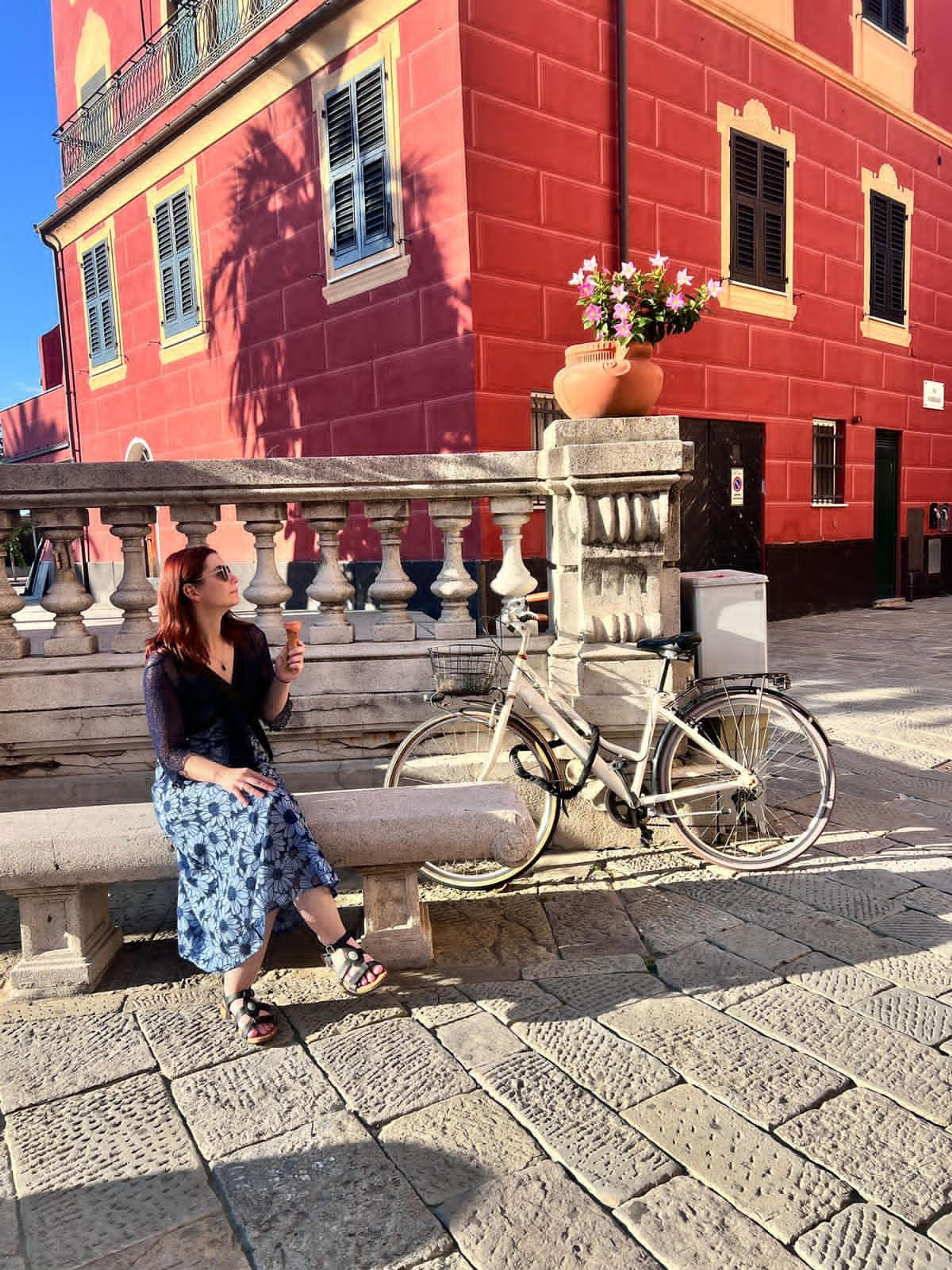 A woman enjoys gelato while sitting on a stone bench.