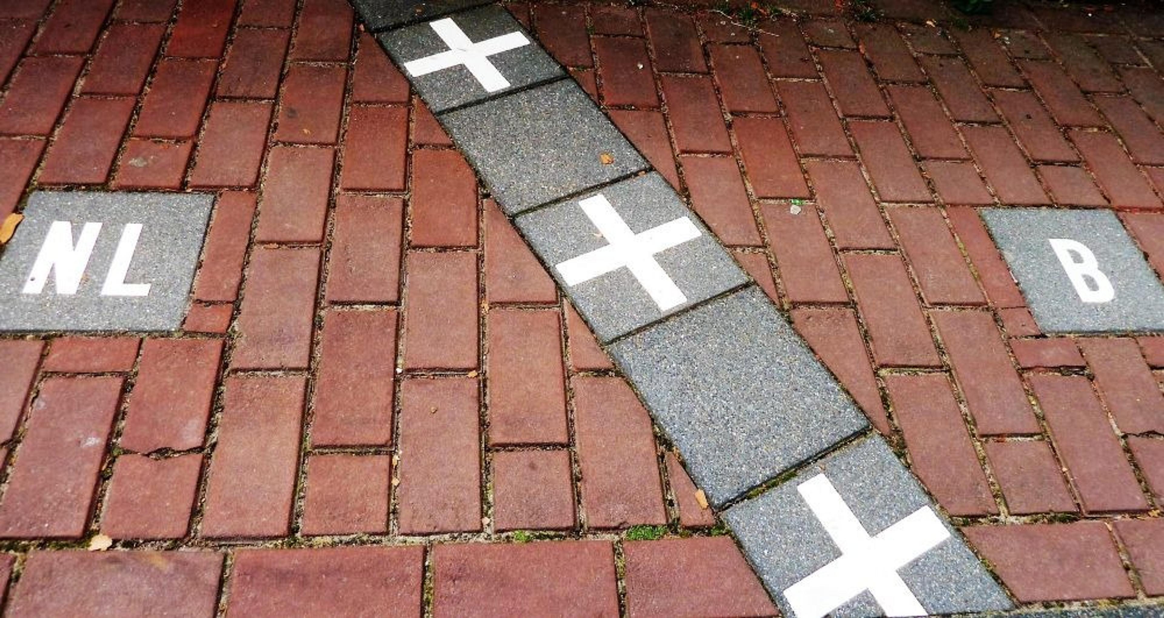 A line marking the border between the Netherlands and Belgium is displayed on a brick pathway in Baarle.