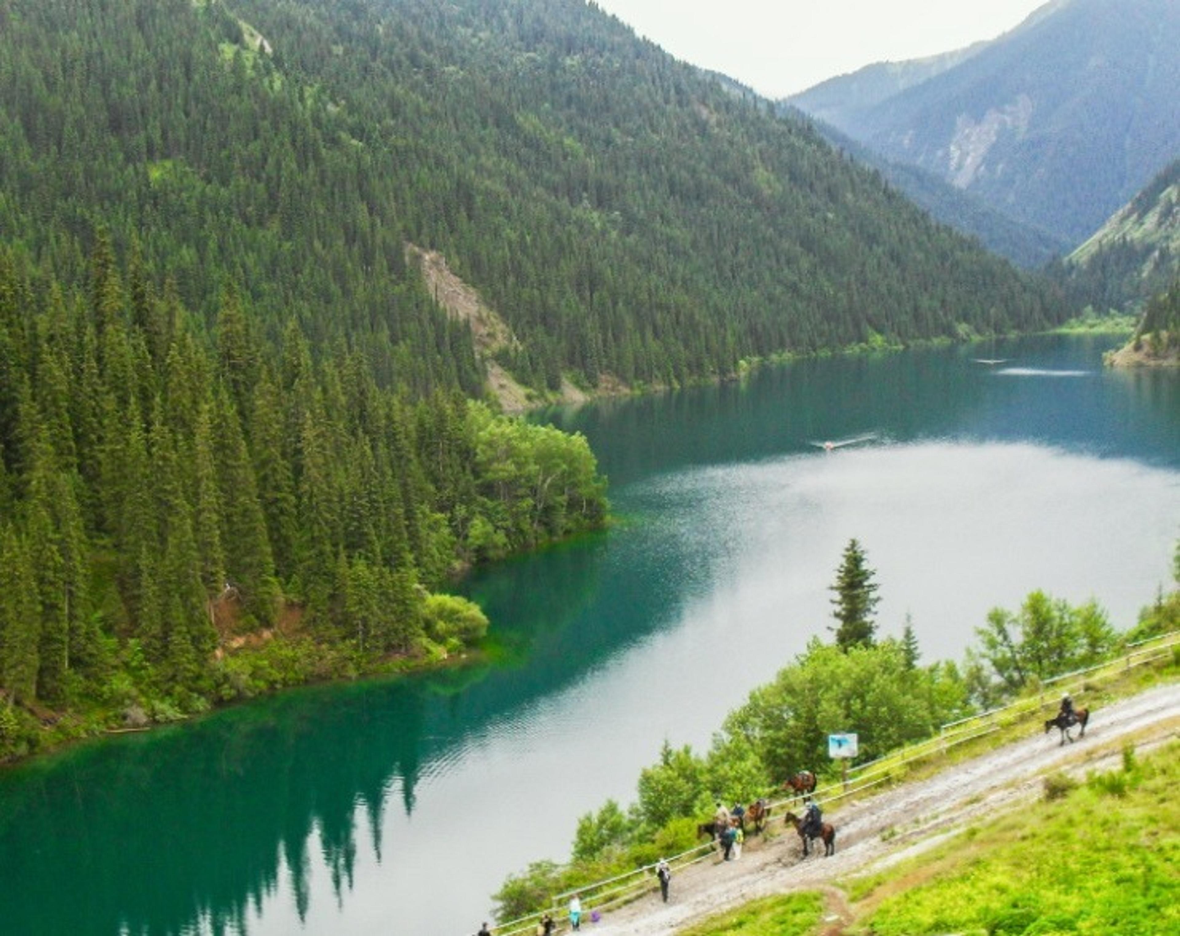 Picturesque Kolsai Lake in Kazakhstan, nestled among lush green mountains and surrounded by dense forests.