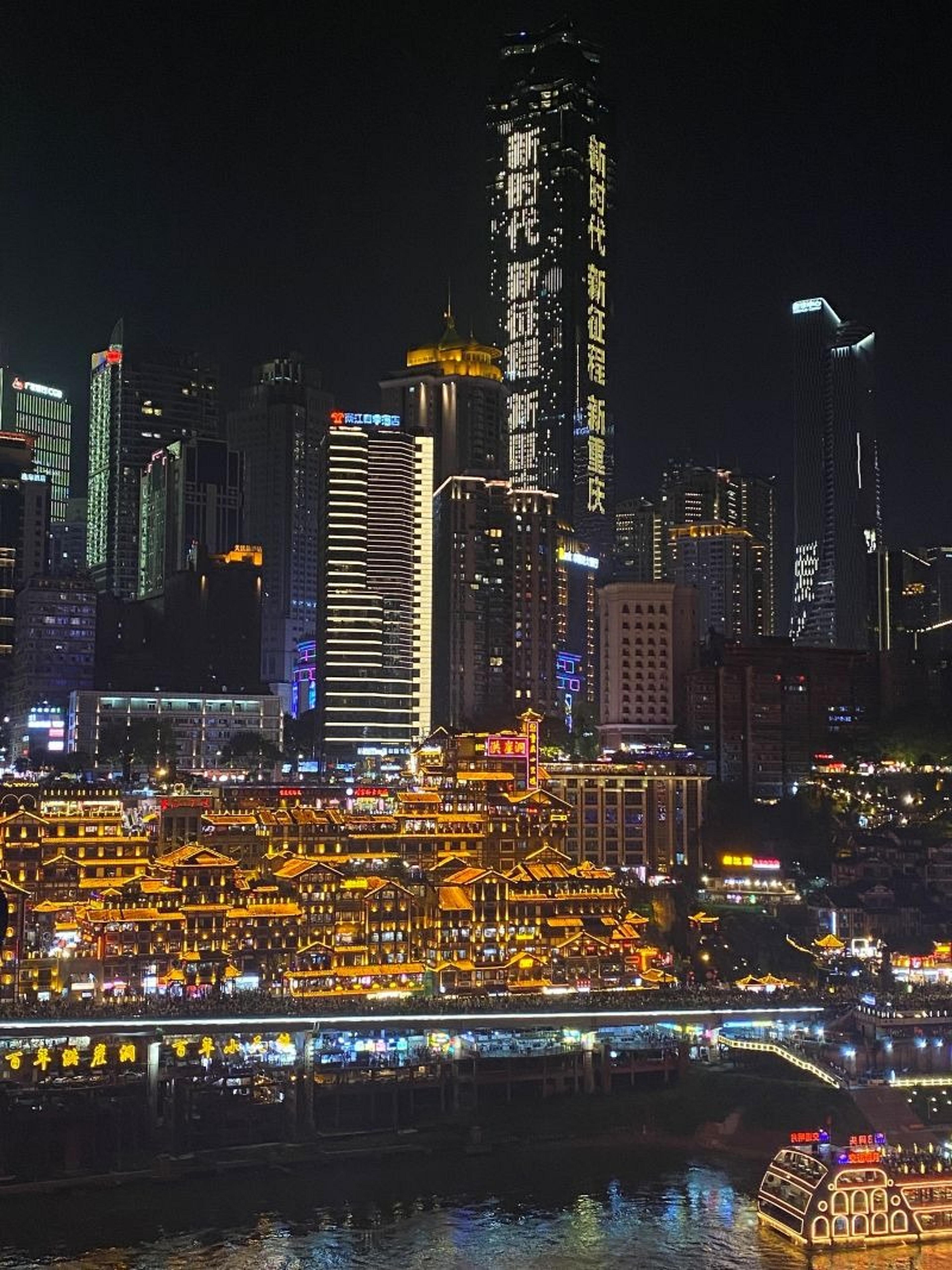 A vibrant night view of Hongyadong in Chongqing, China, with its glowing traditional architecture set against a backdrop of modern skyscrapers.