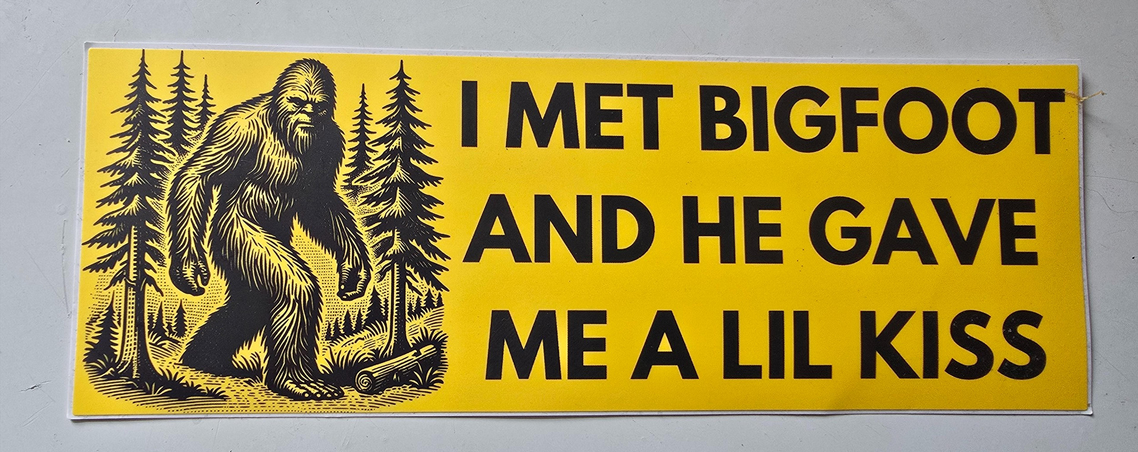 A whimsical sticker features Bigfoot amid trees with the humorous text, "I met Bigfoot and he gave me a lil kiss."