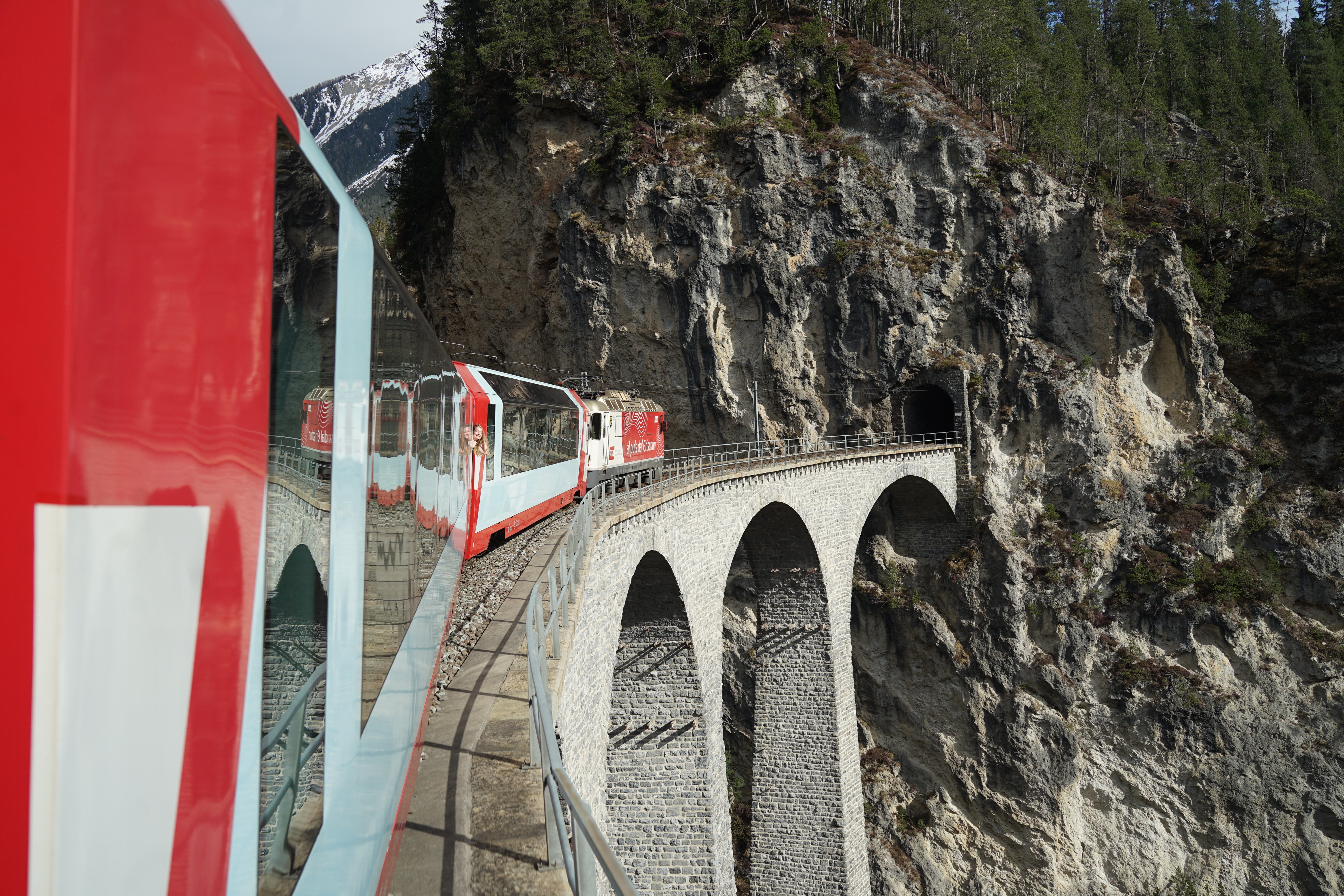 A red train crosses the dramatic Landwasser Viaduct in the Swiss Alps.