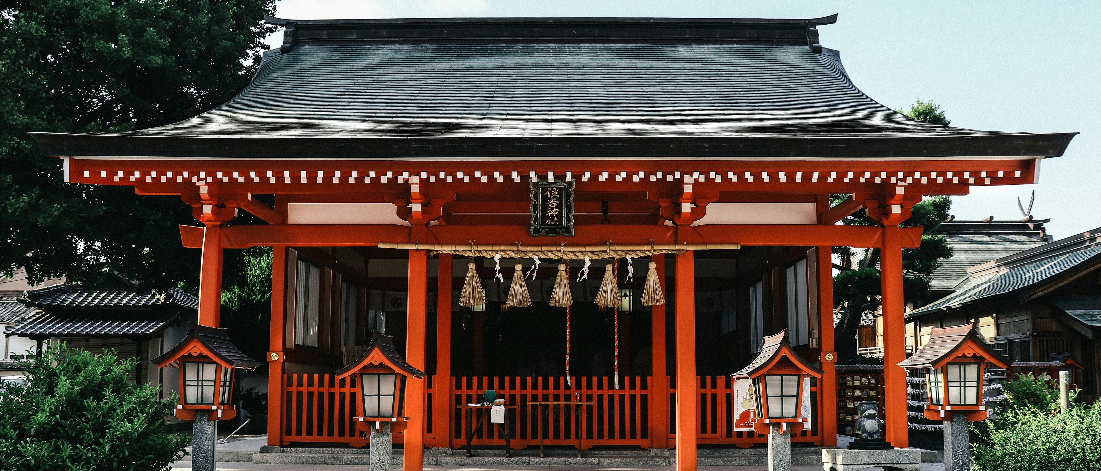 A vibrant red Shinto shrine stands prominently in Kyoto, Japan, adorned with traditional lanterns and sacred ropes.